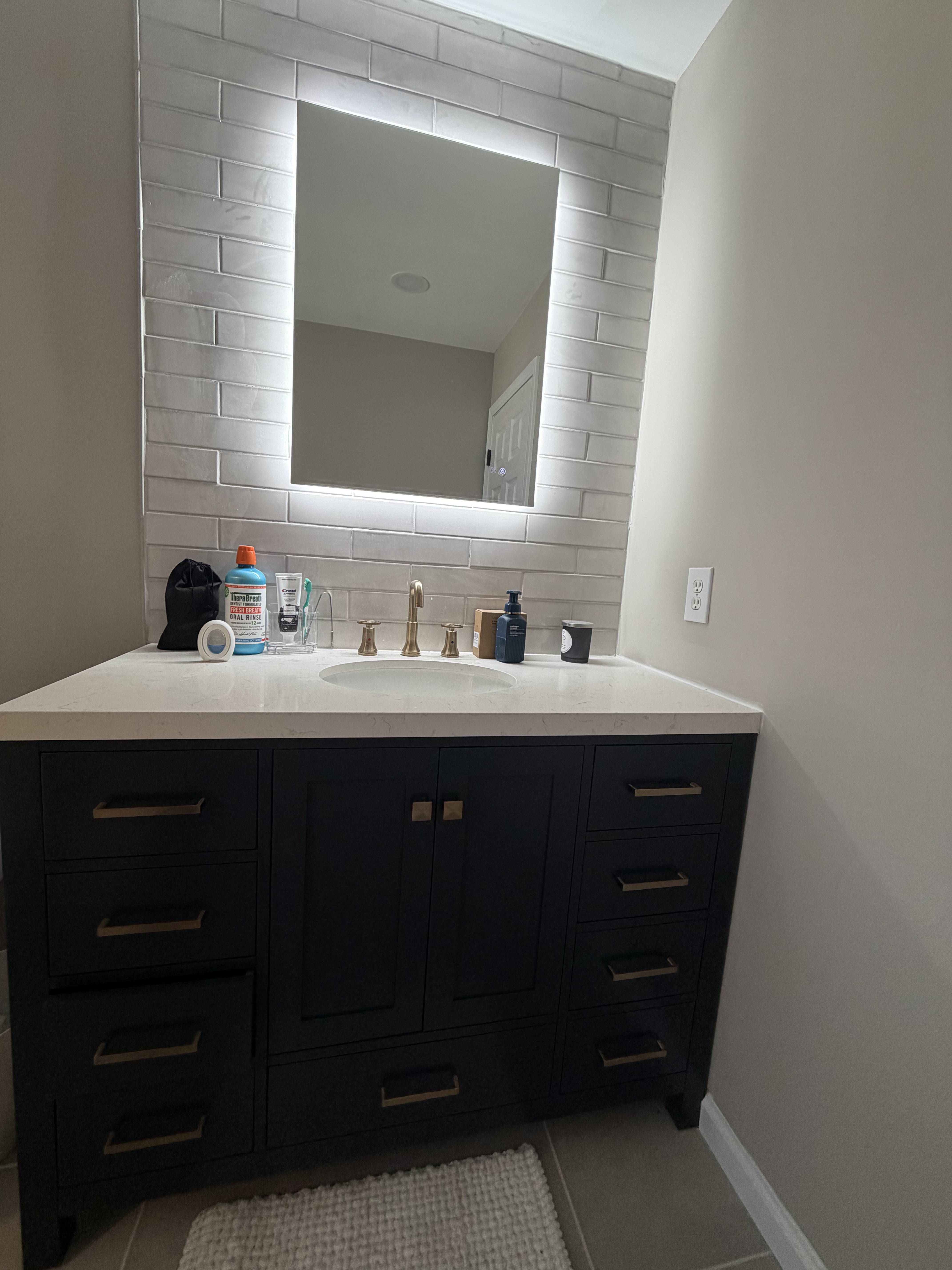 Navy vanity close-up with white countertop and backlit mirror
