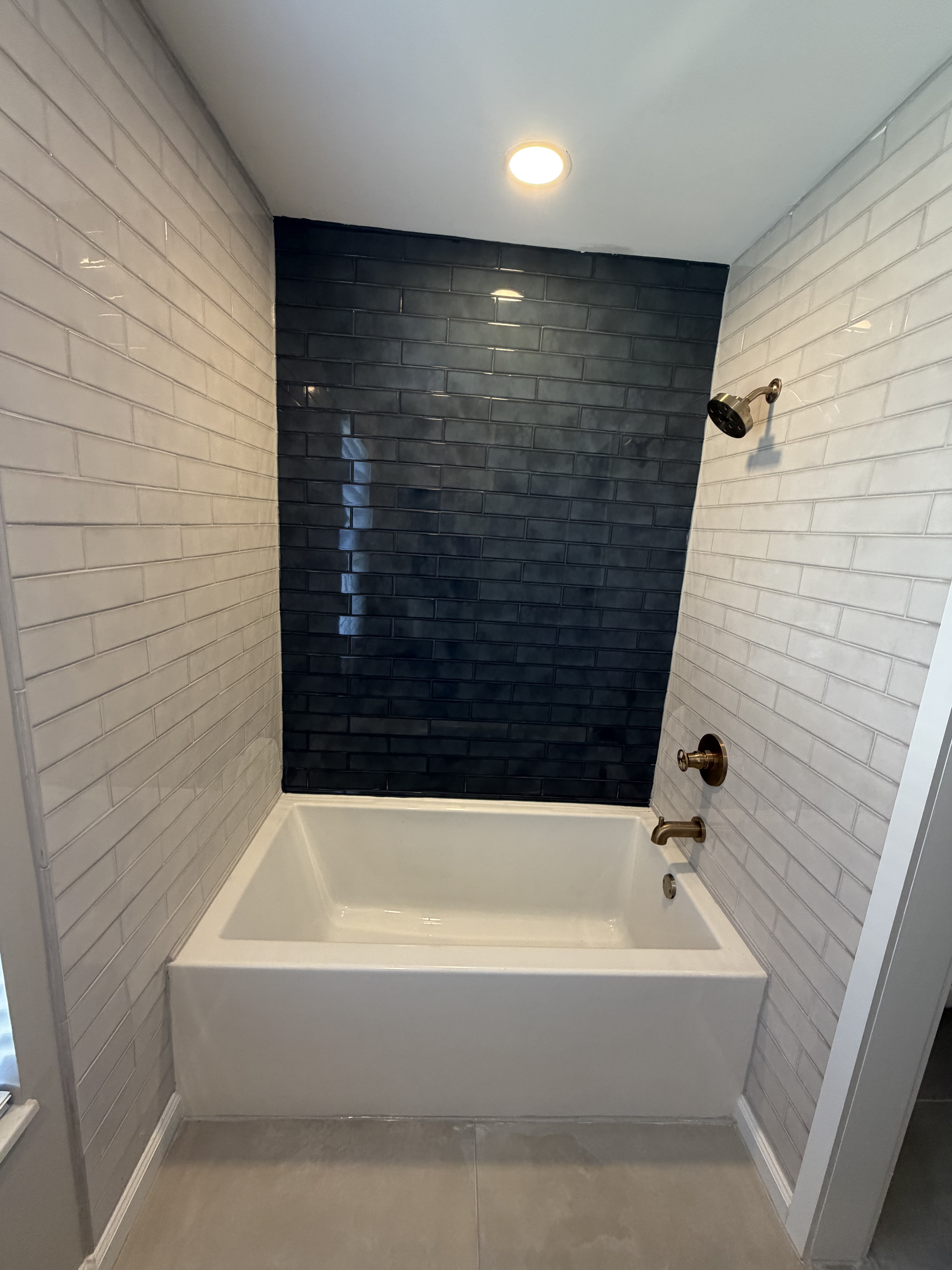 Soaking tub with navy accent tile wall and bronze shower fixtures