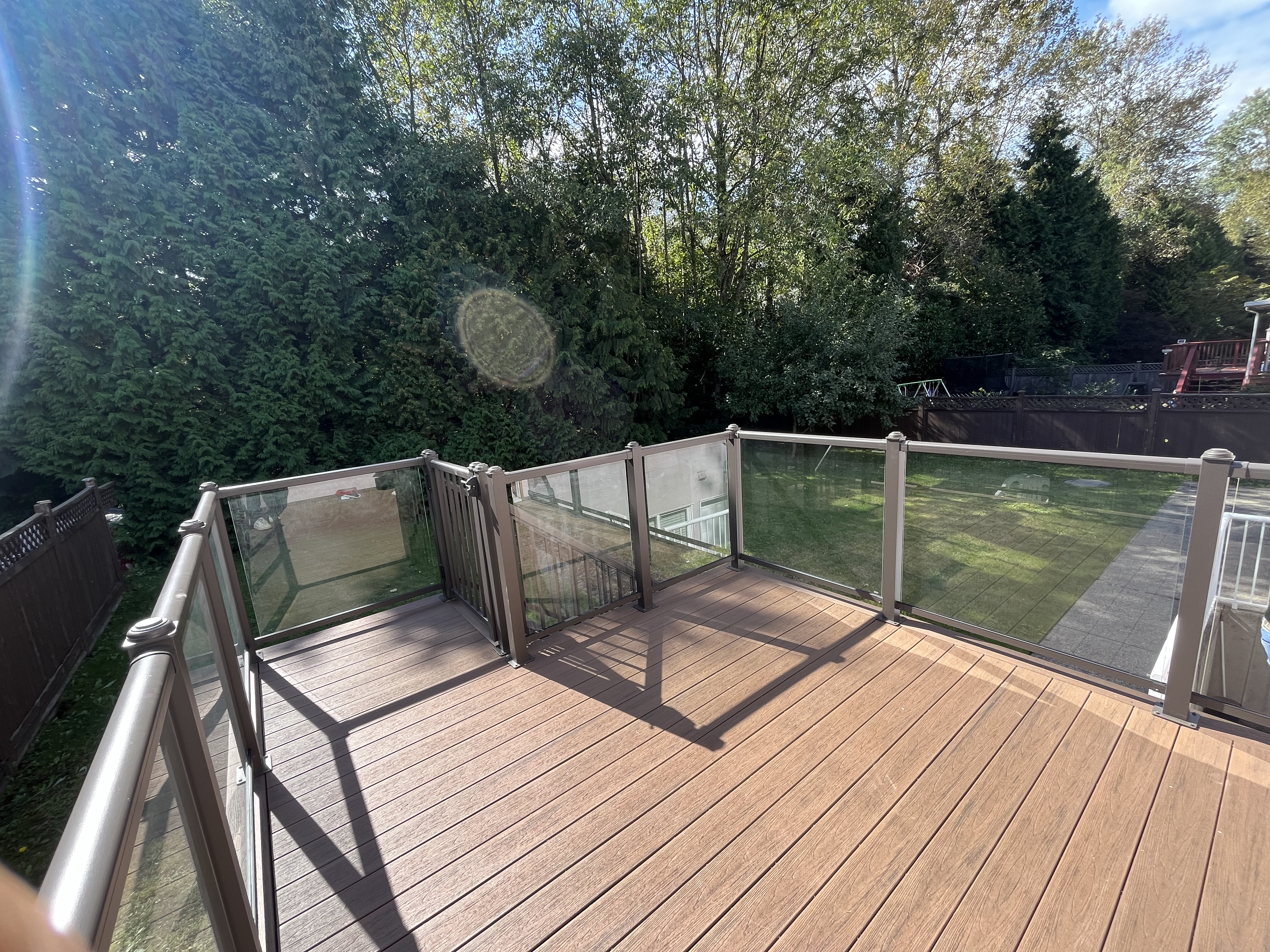 Ryan's composite deck surface with glass railing overlooking the backyard by Tarak Construction