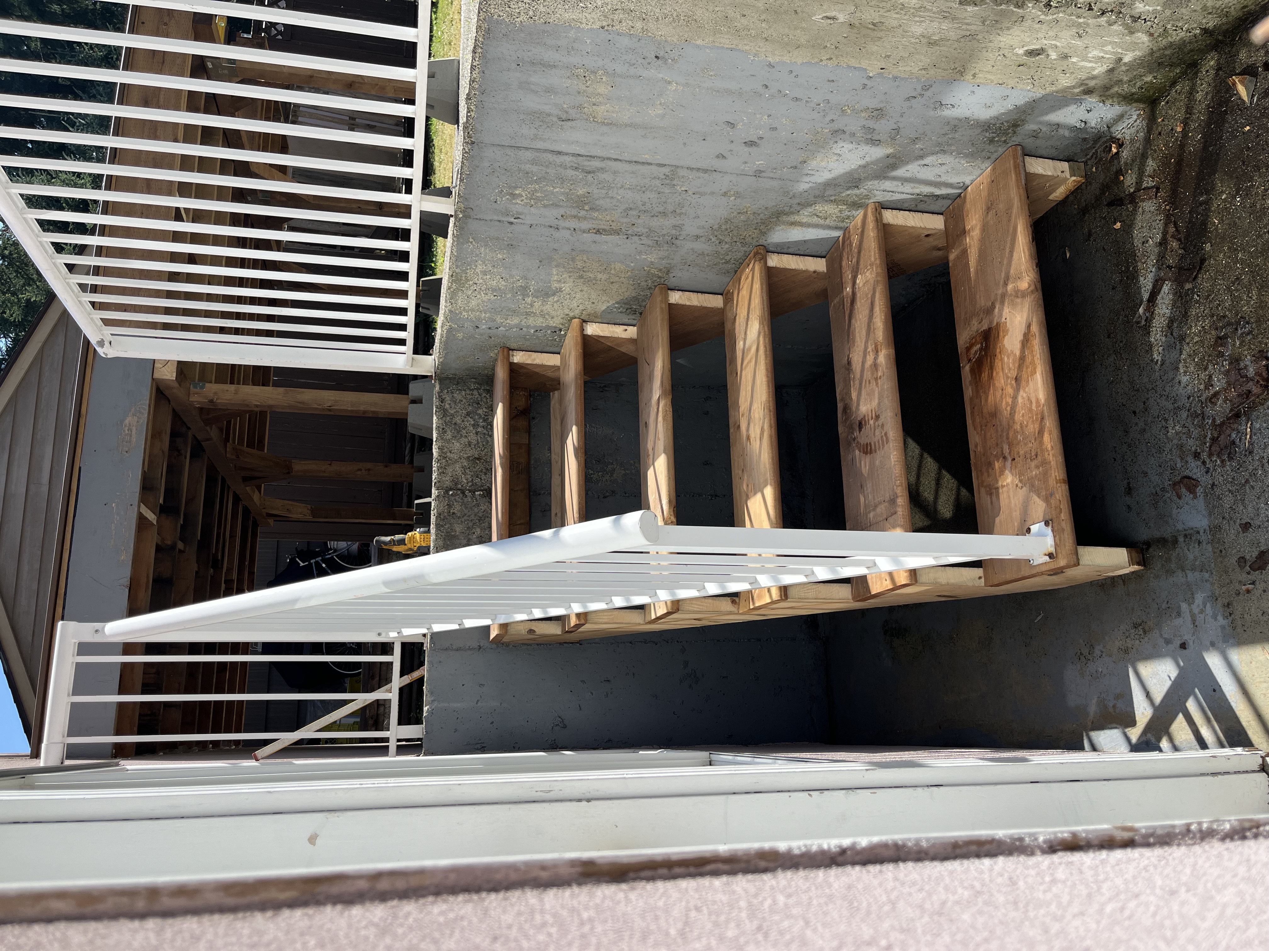 Ryan's basement access stairs with white railing by Tarak Construction
