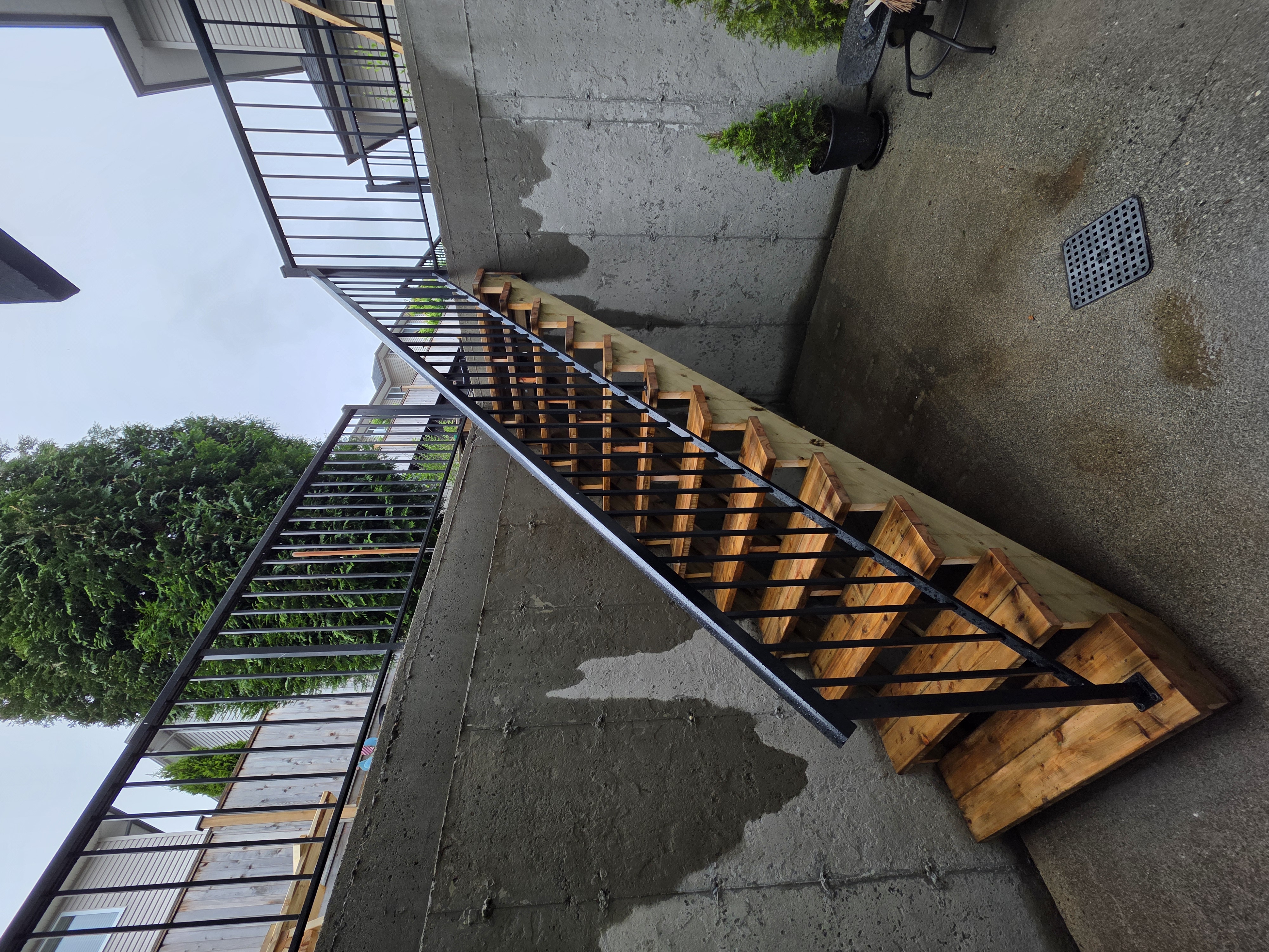 Ash's new basement access stairs with black metal railing by Tarak Construction
