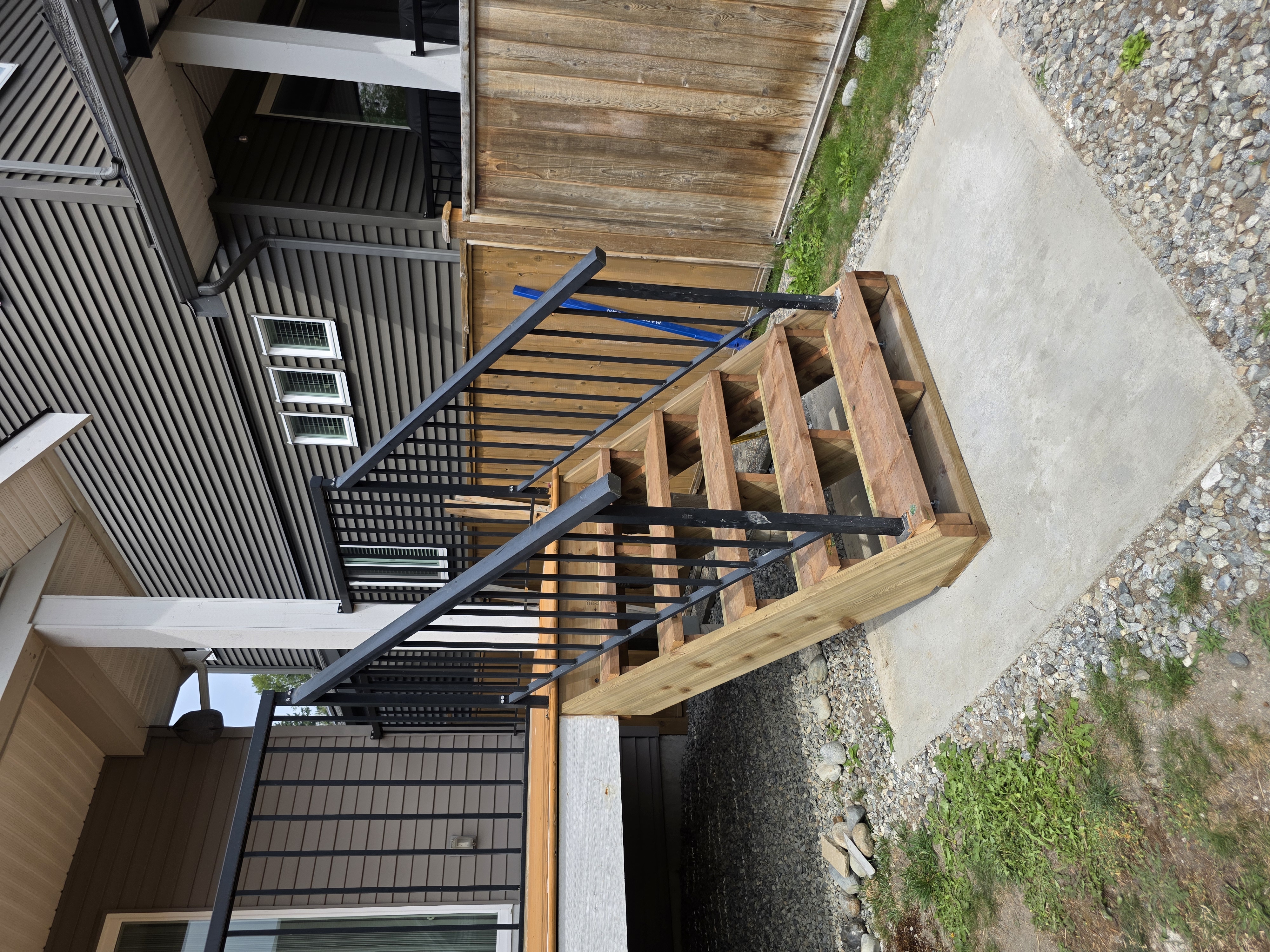 Linda's pressure treated deck stairs with black metal railing by Tarak Construction