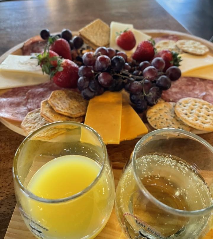Grazing board with cheeses, grapes, strawberries, salami, and mimosa glasses