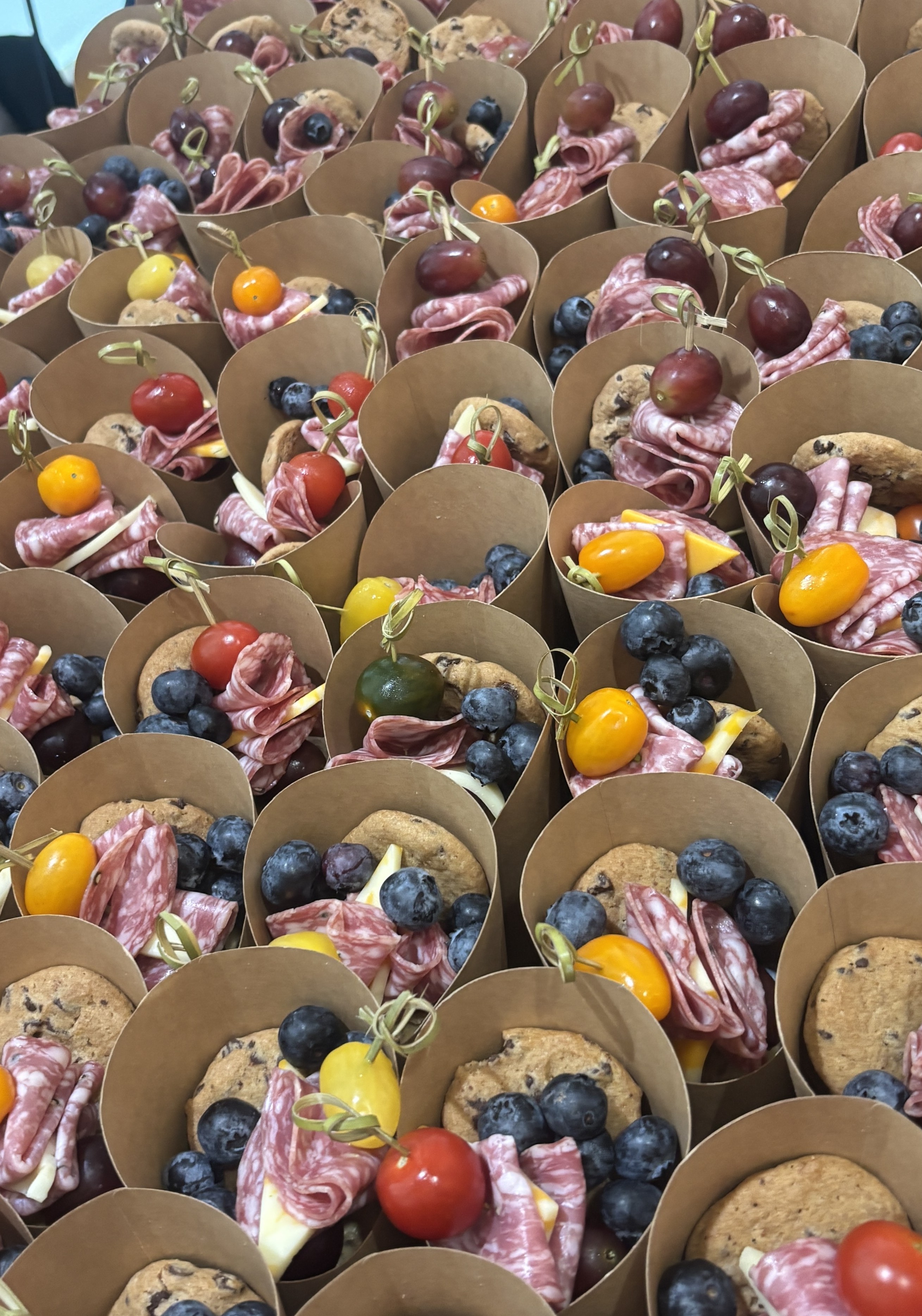 Individual grazing cups with salami, blueberries, tomatoes, and cookies