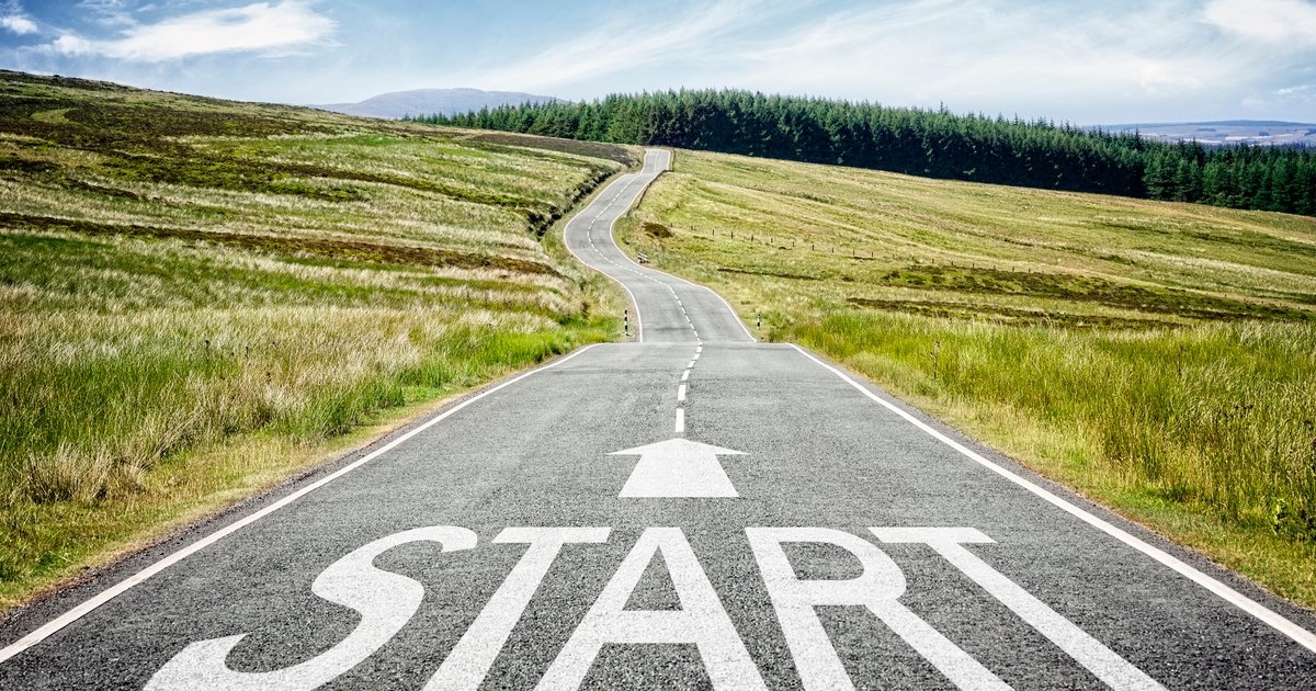 A winding road with START painted on the asphalt and an arrow pointing forward — the journey begins here