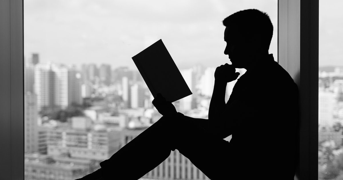 A man in silhouette reading a book by a window — the journey Beyond Discipline begins on the page