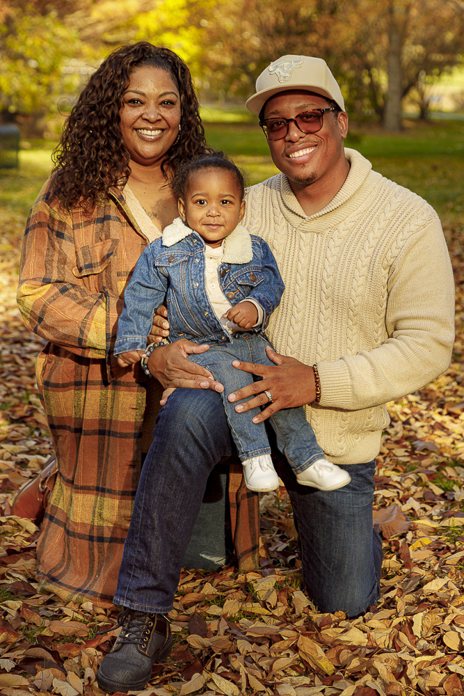 Couple holding their baby surrounded by golden fallen autumn leaves — IDT Photo fall portrait