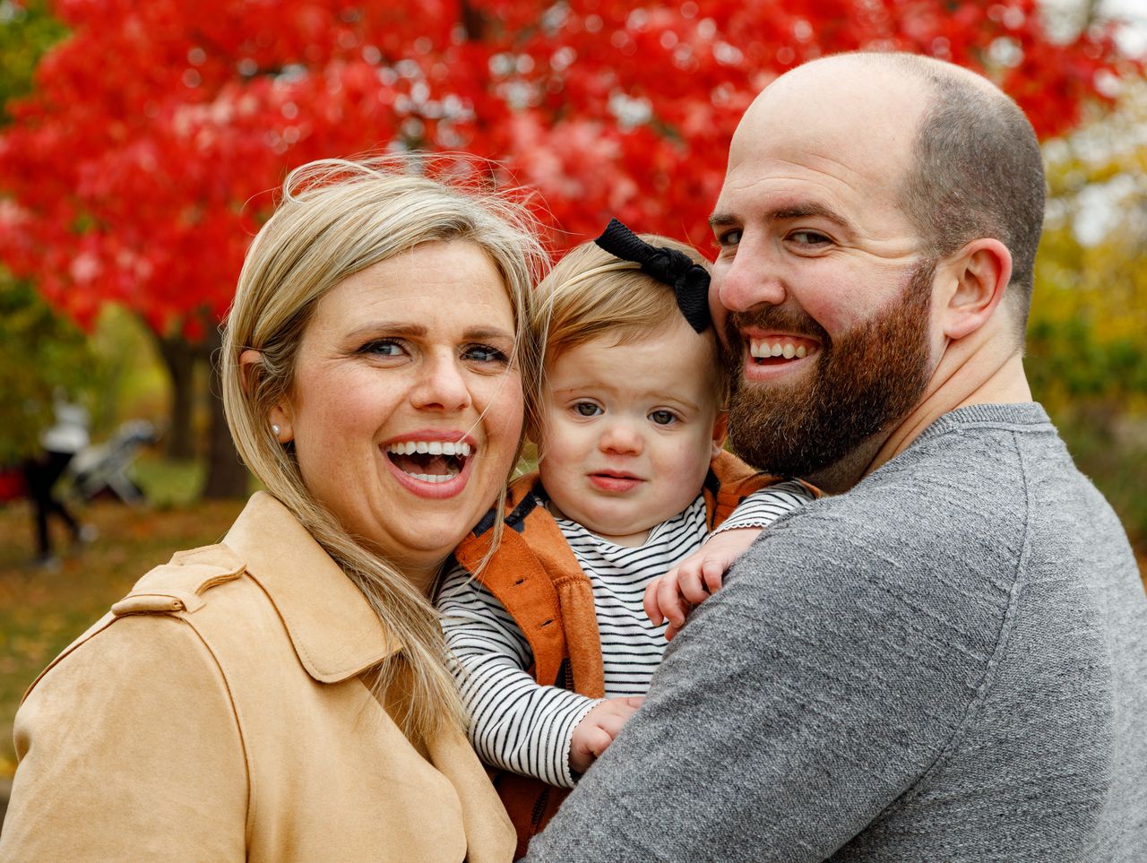 Mother laughing with family under red maple tree