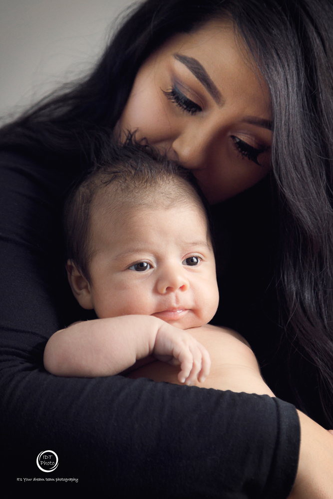3-month baby resting chin on mom's arm, wide-eyed and alert — IDTPhoto sitter session