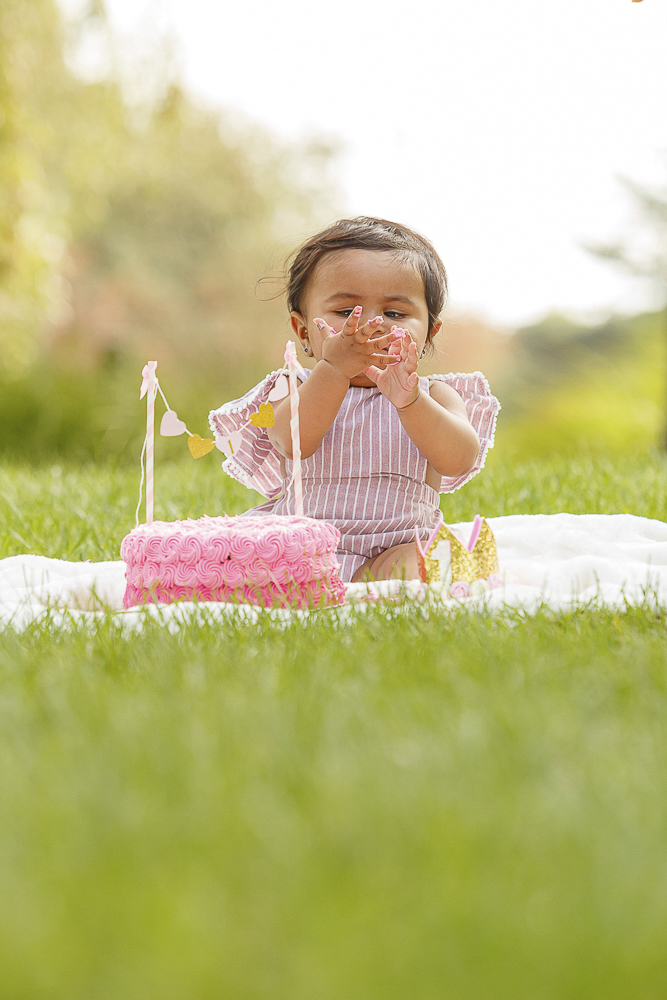 Baby tasting frosting during first birthday cake smash session — IDTPhoto