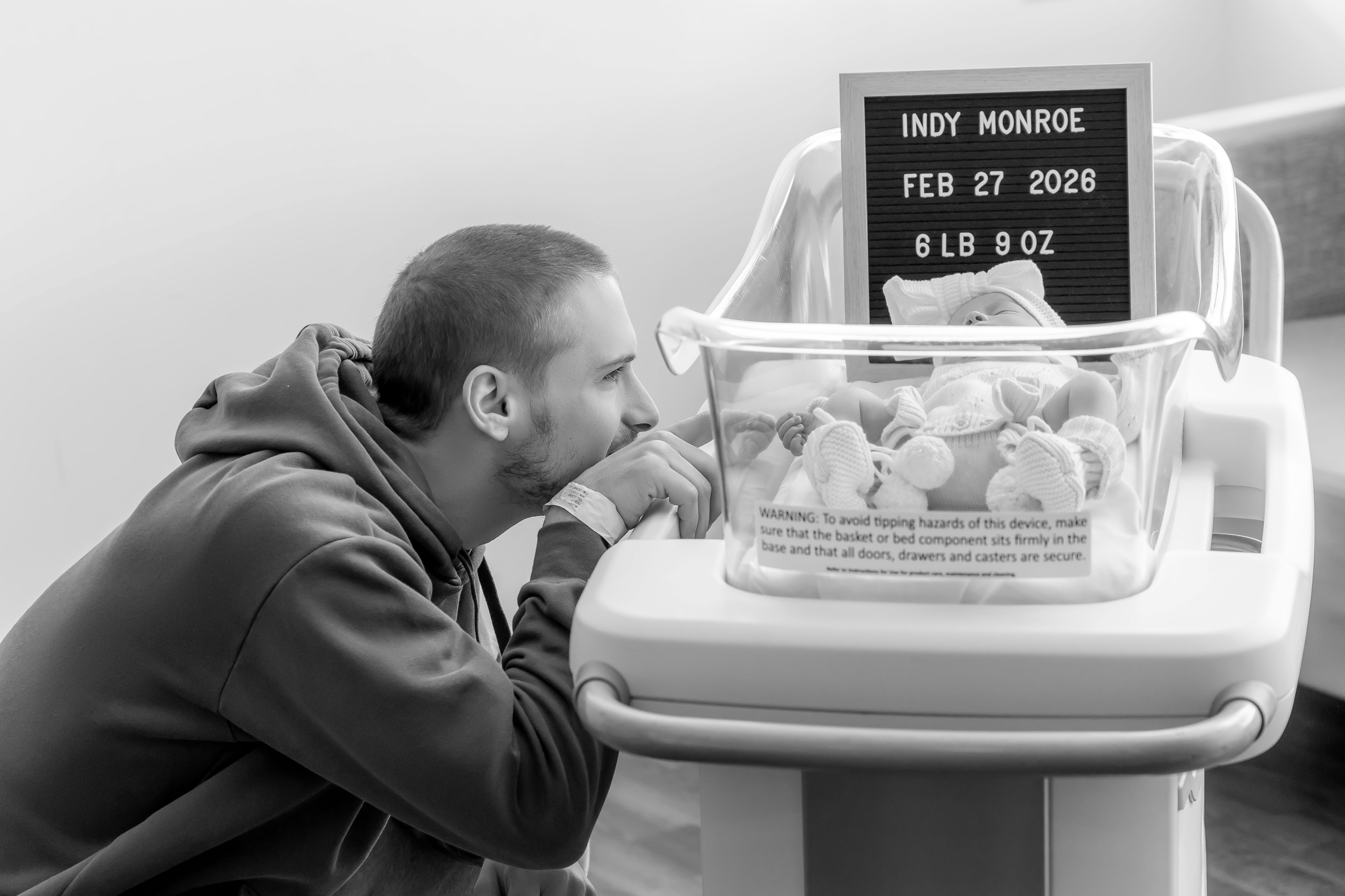 Fresh 48 black & white — dad gazing in wonder at newborn daughter in hospital bassinet