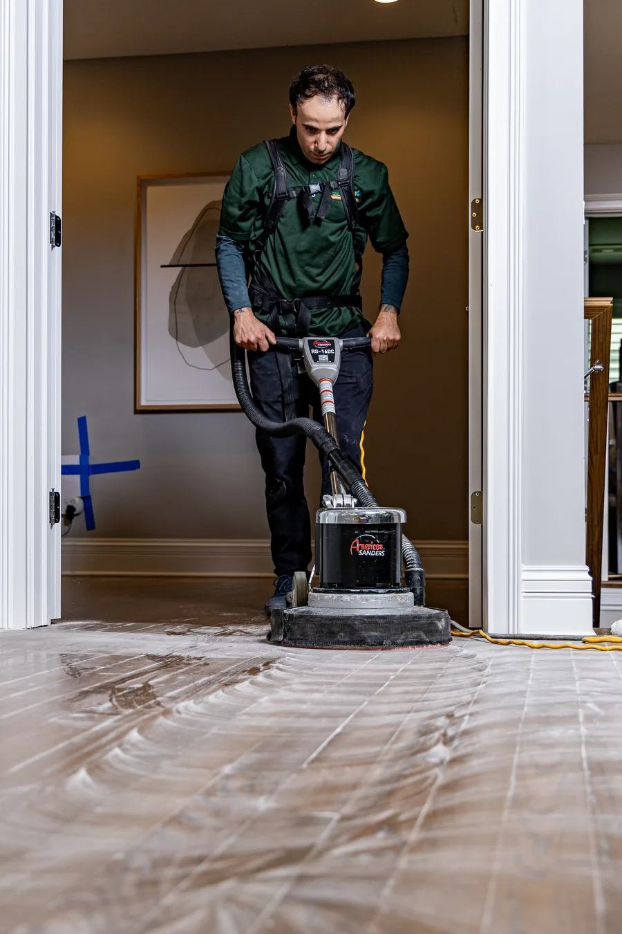 Buff and Coat worker preparing a wood floor with floor sanding equipment.