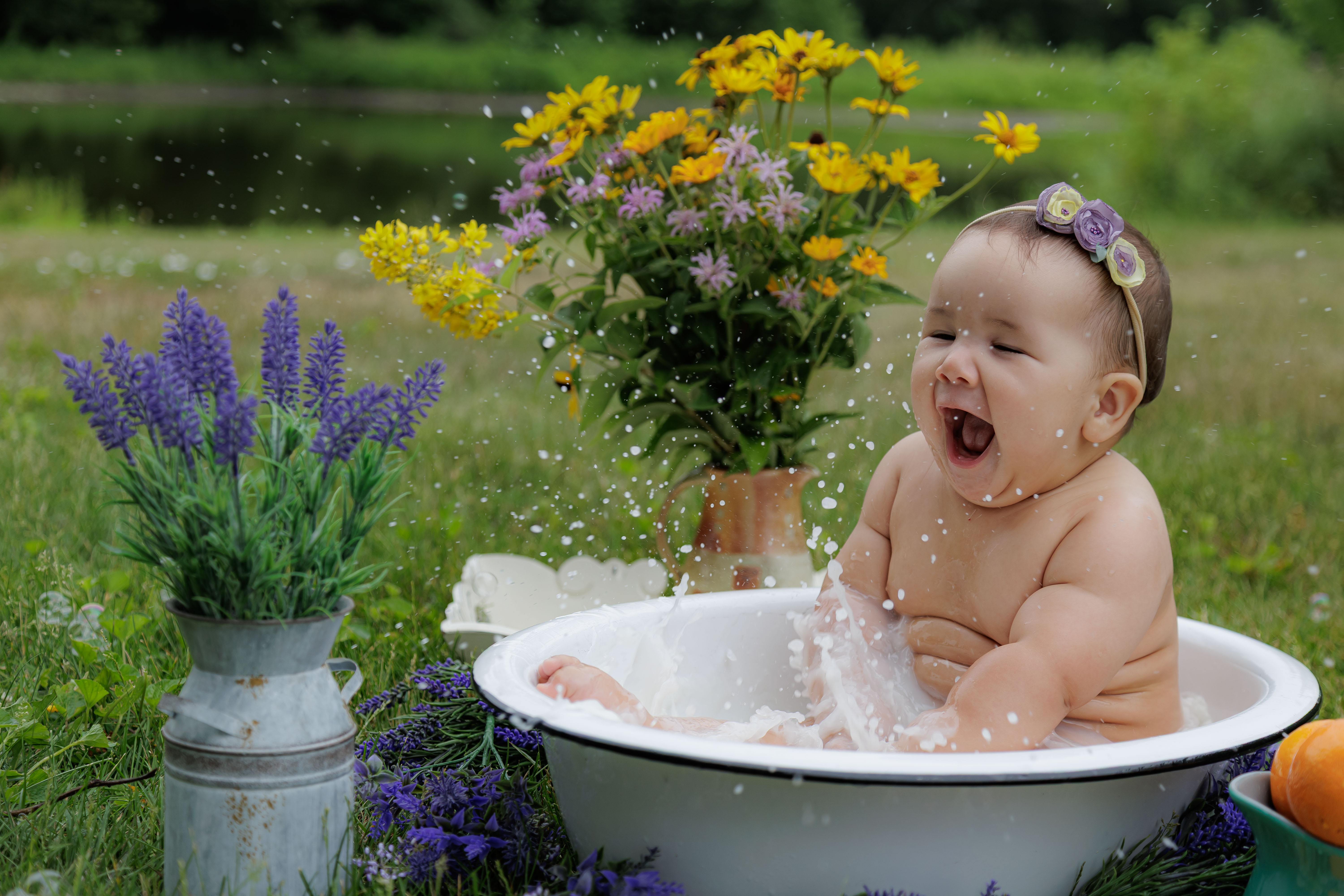 Baby girl laughing big with flowers and lavender surrounding her outdoor milk bath tub — IDTPhoto milestone session Aurora IL