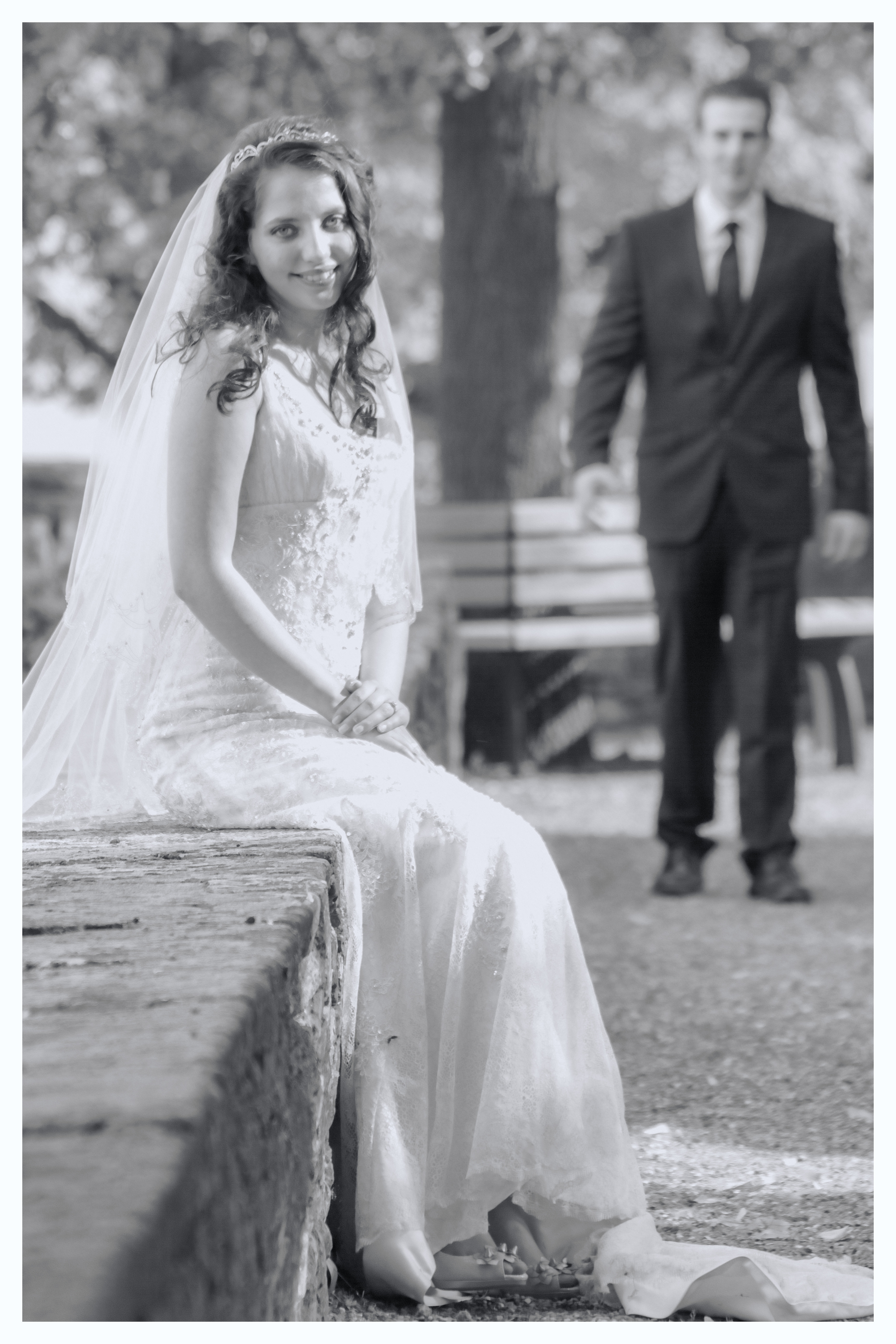 Bride kissing groom on the cheek while he smiles — outdoor wedding portrait with green background — IDTPhoto Chicagoland