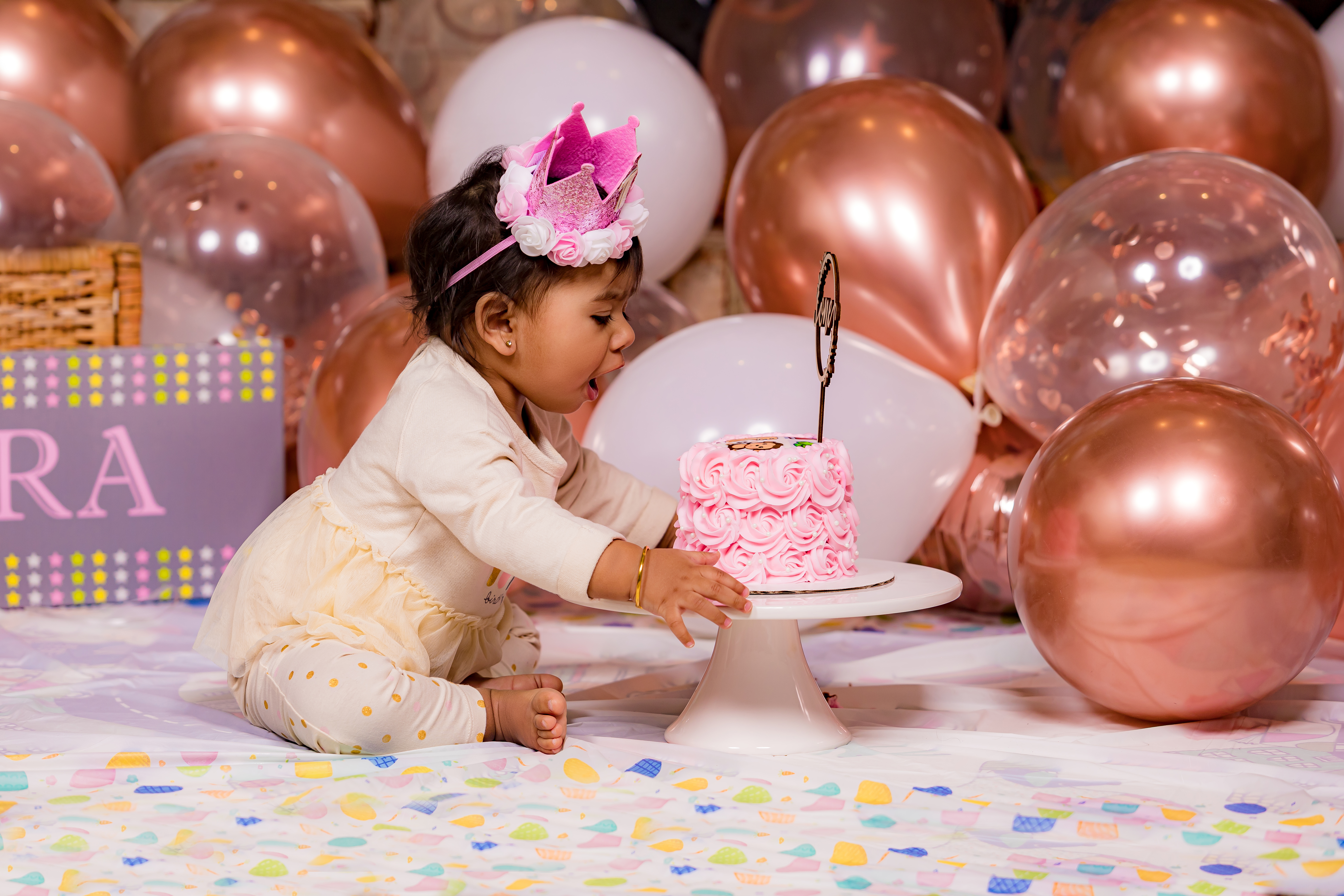 Baby reaching for pink birthday cake with mouth open — cake smash anticipation moment by IDTPhoto