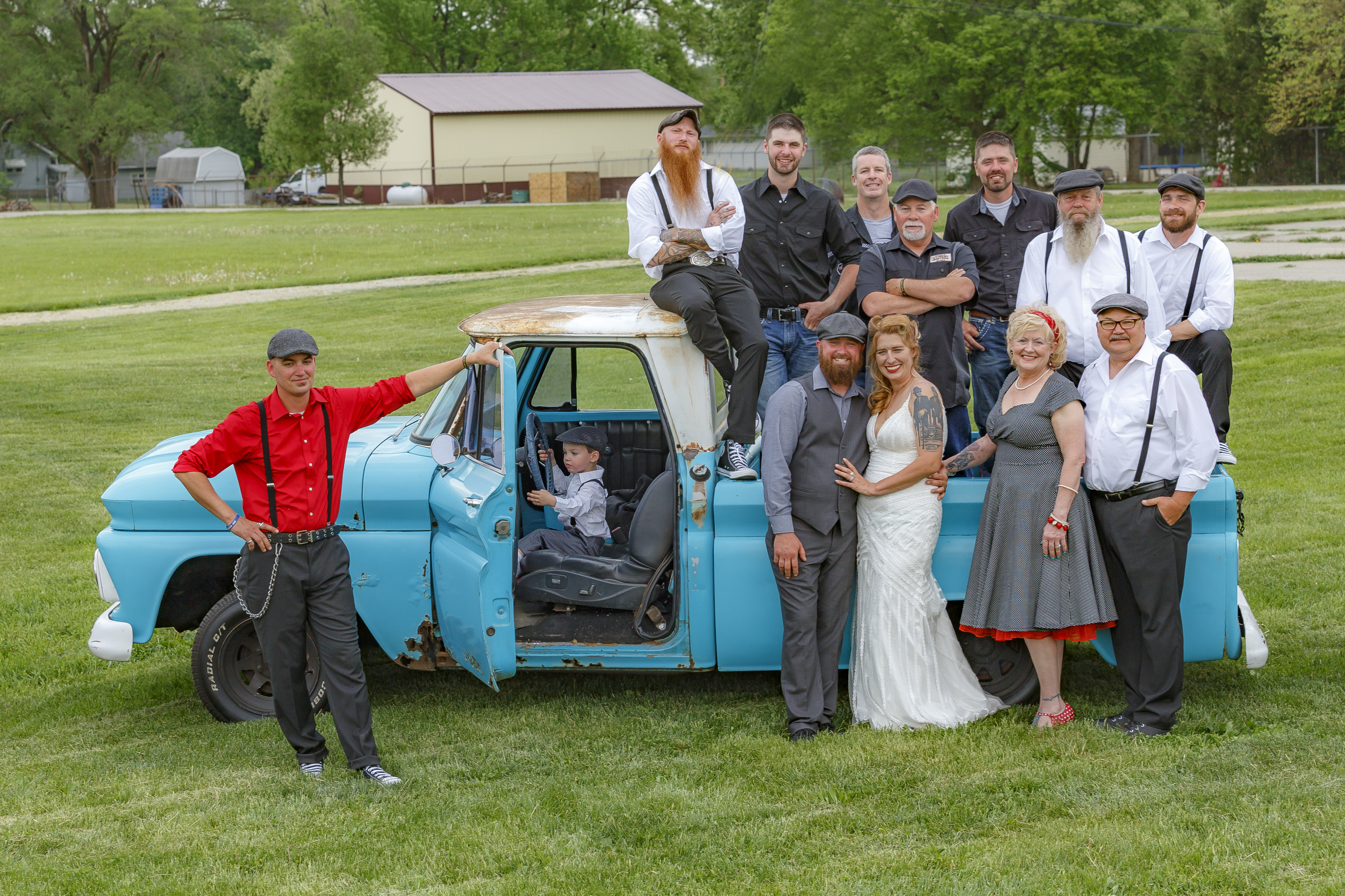 Full wedding party crowded around and on top of vintage teal pickup truck with big smiles — IDTPhoto wedding photography