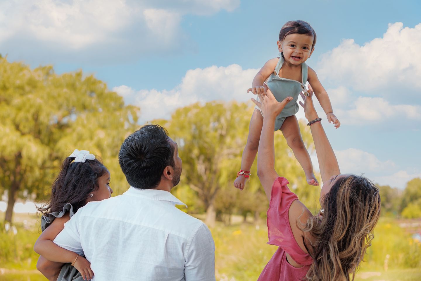 Baby joyfully tossed into the air against blue sky
