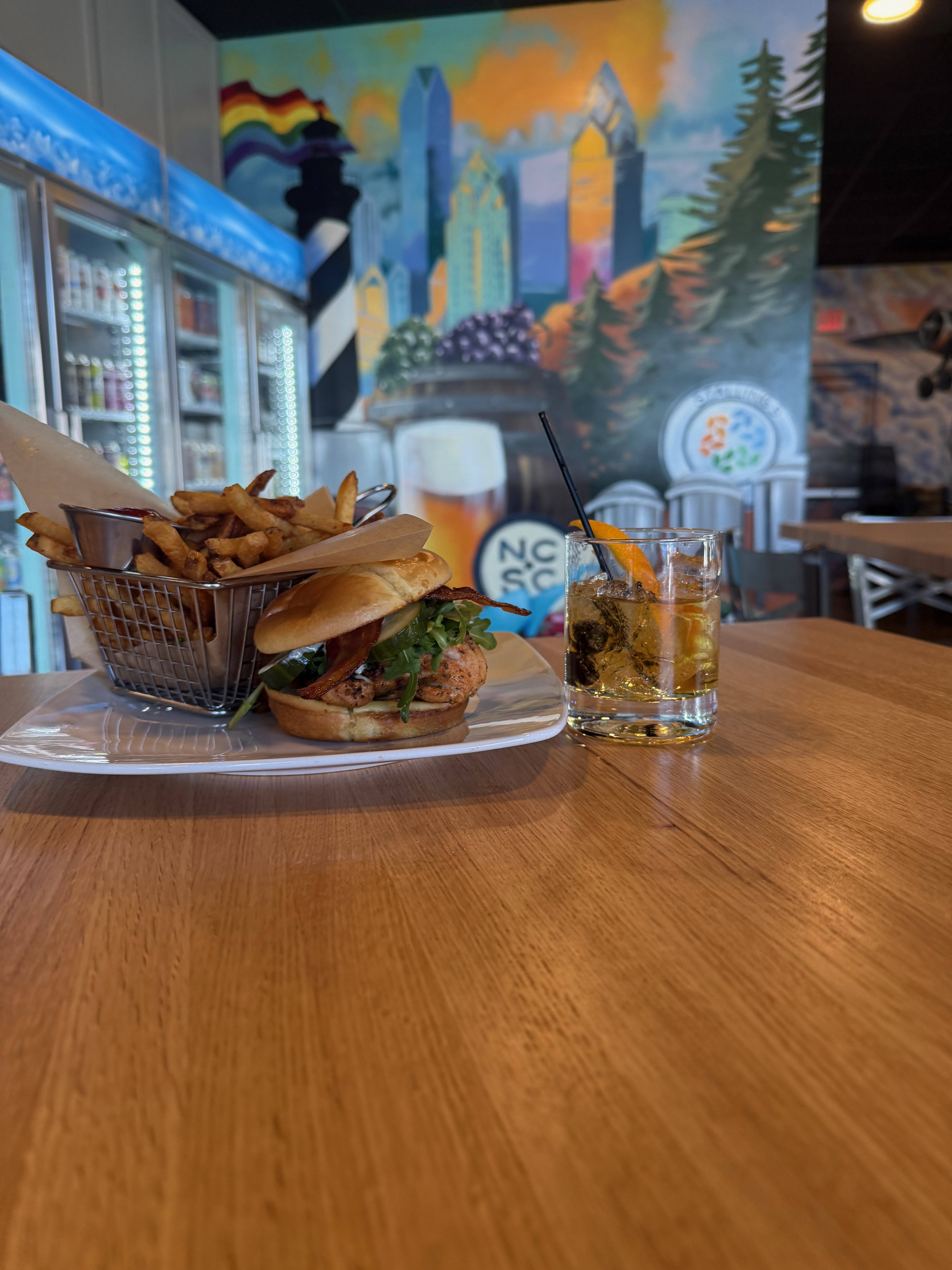 Burger with fries and cocktail at The VRTX with colorful mural