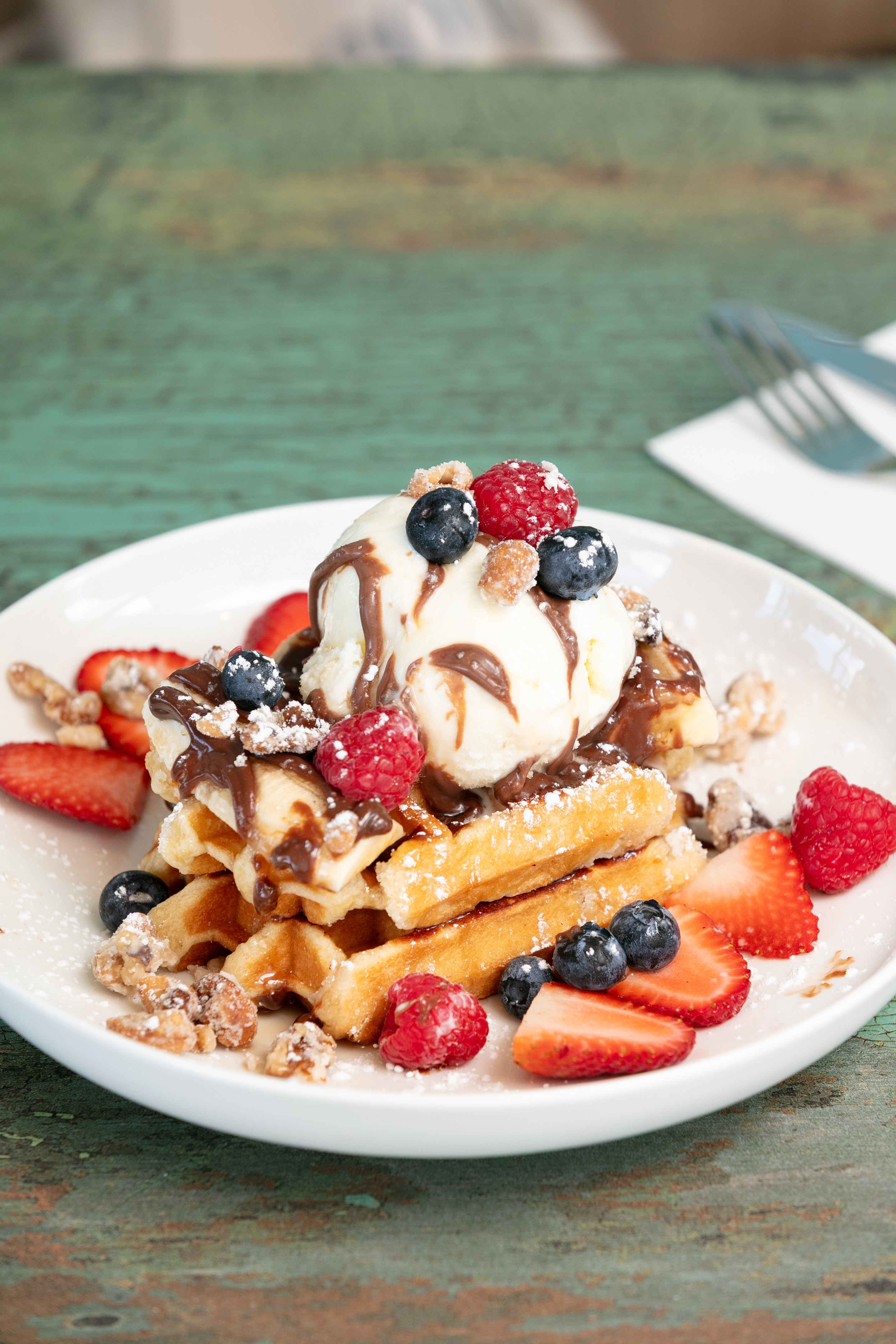 Golden waffles topped with vanilla ice cream, chocolate sauce, fresh strawberries, raspberries and blueberries at Wellington Square Wallan