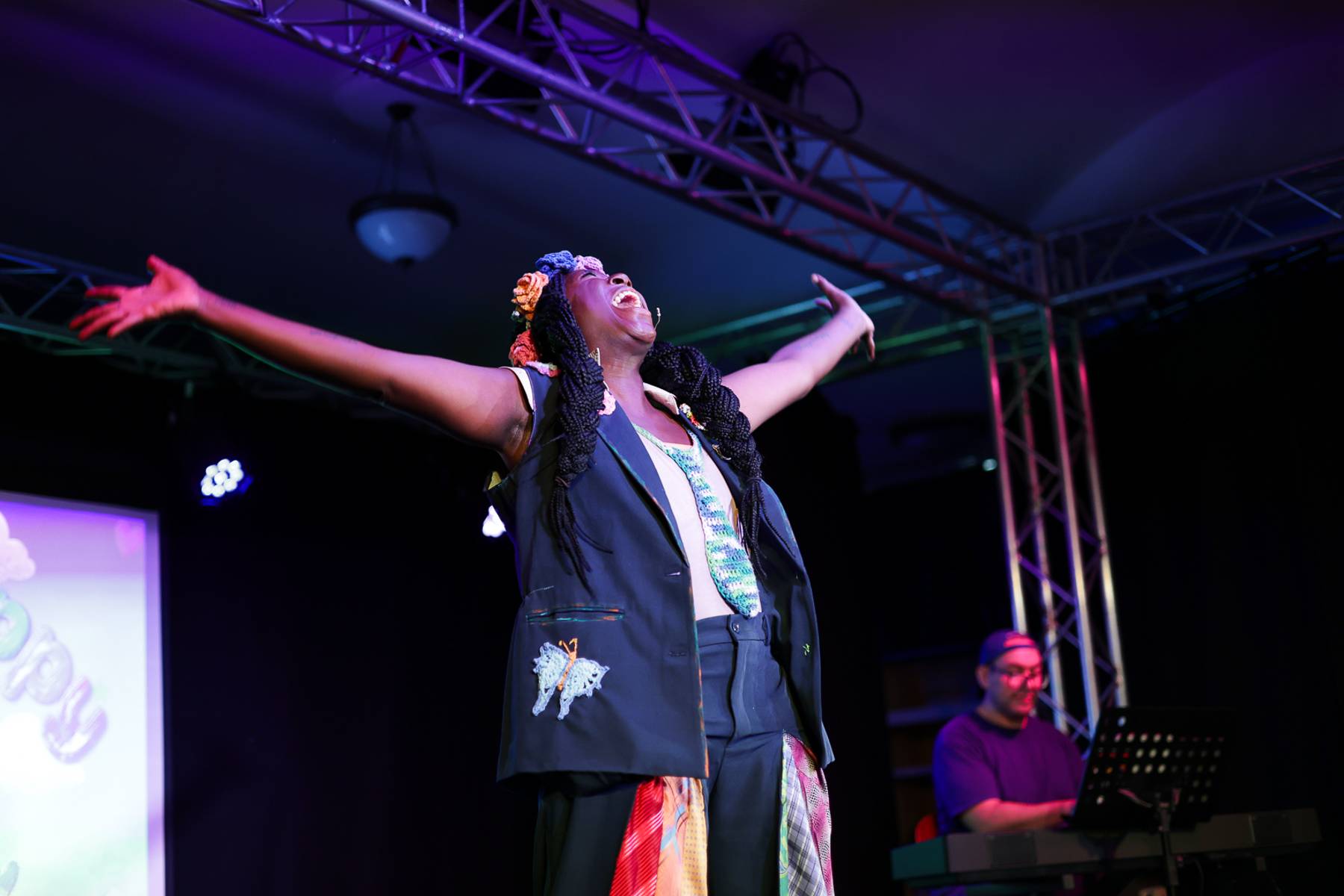 Vasthy on stage with arms wide, singing with joy
