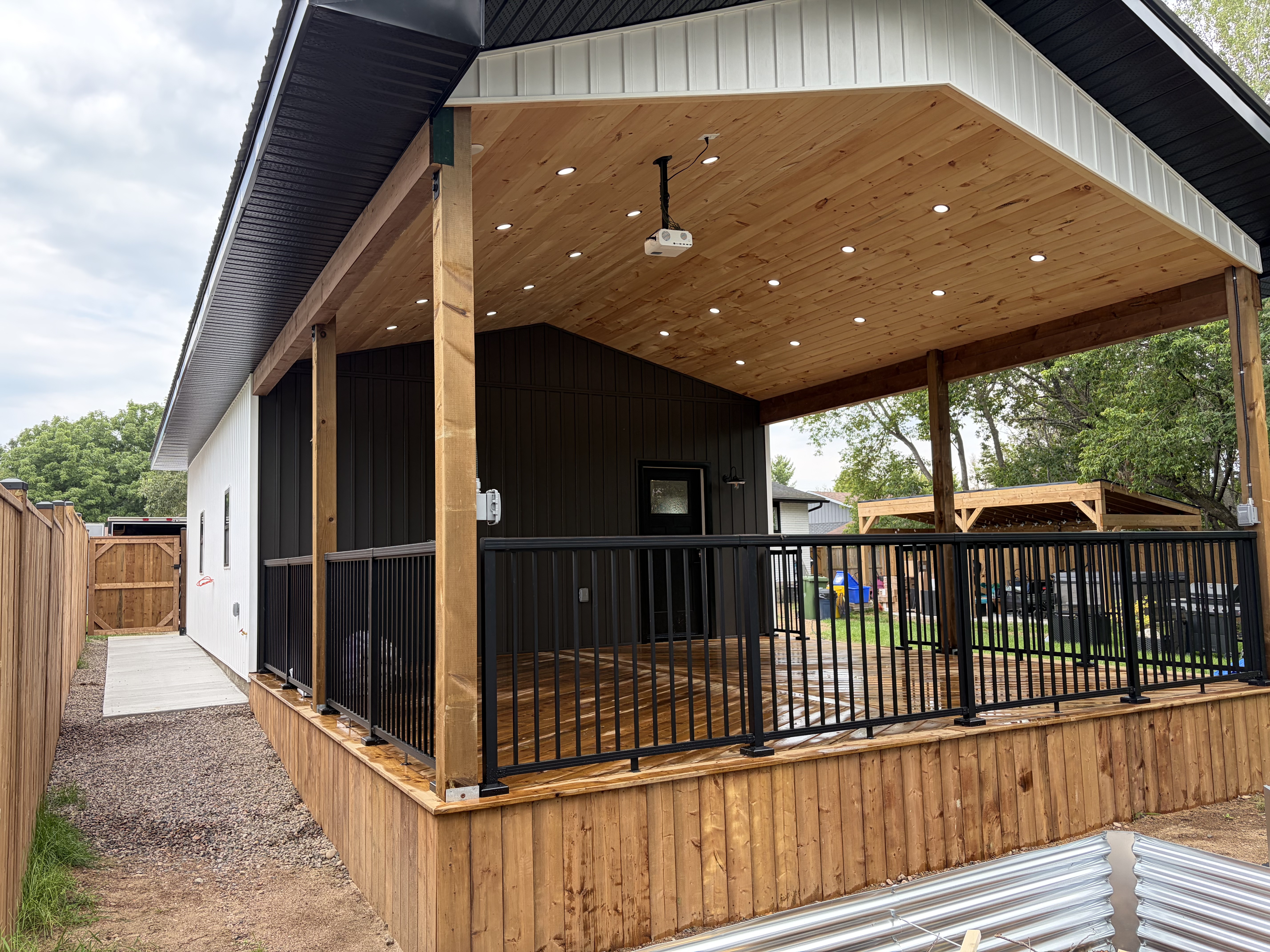 Covered deck with cedar ceiling and pot lights attached to garage