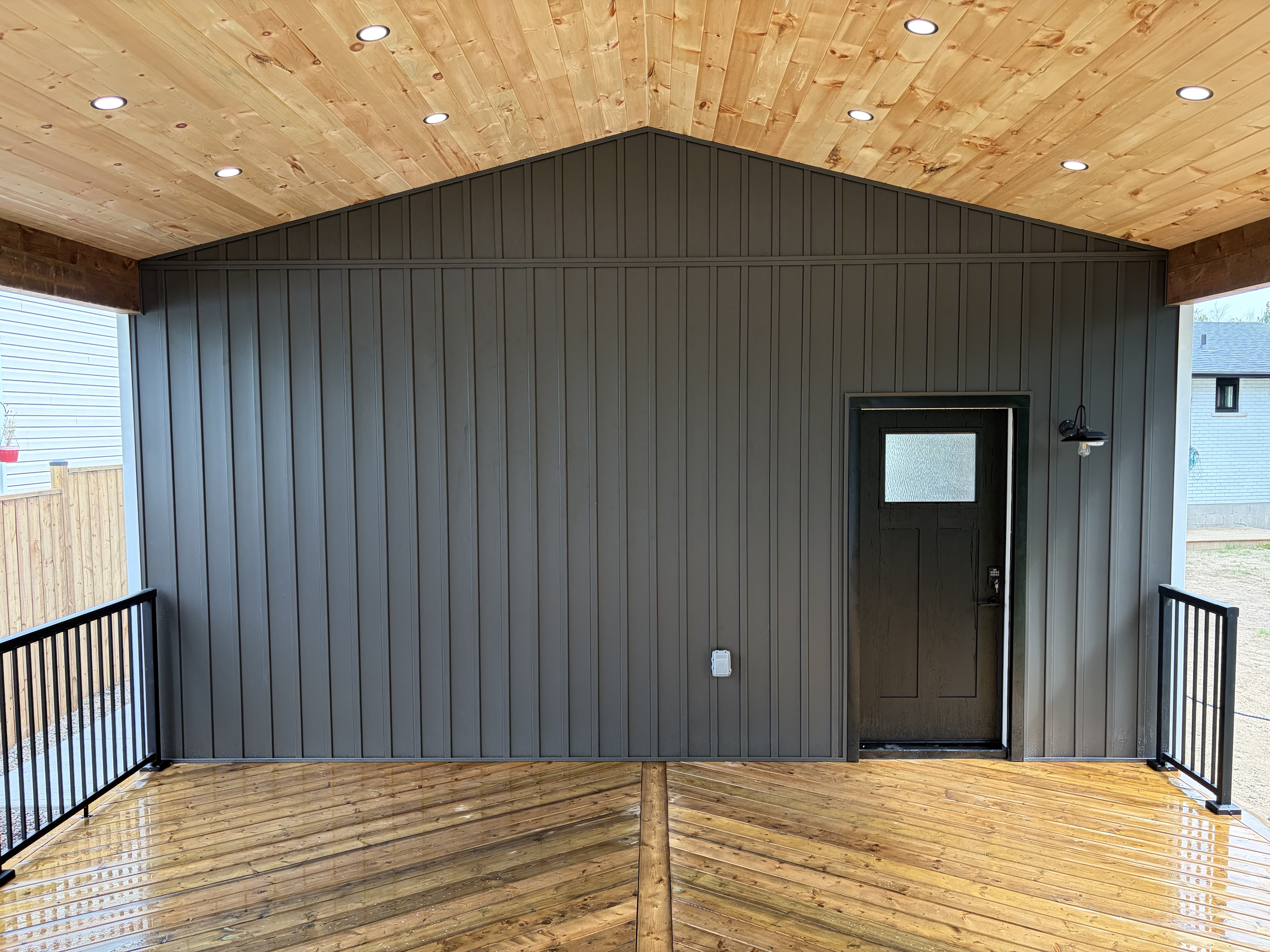 Garage interior covered deck with black siding and entry door