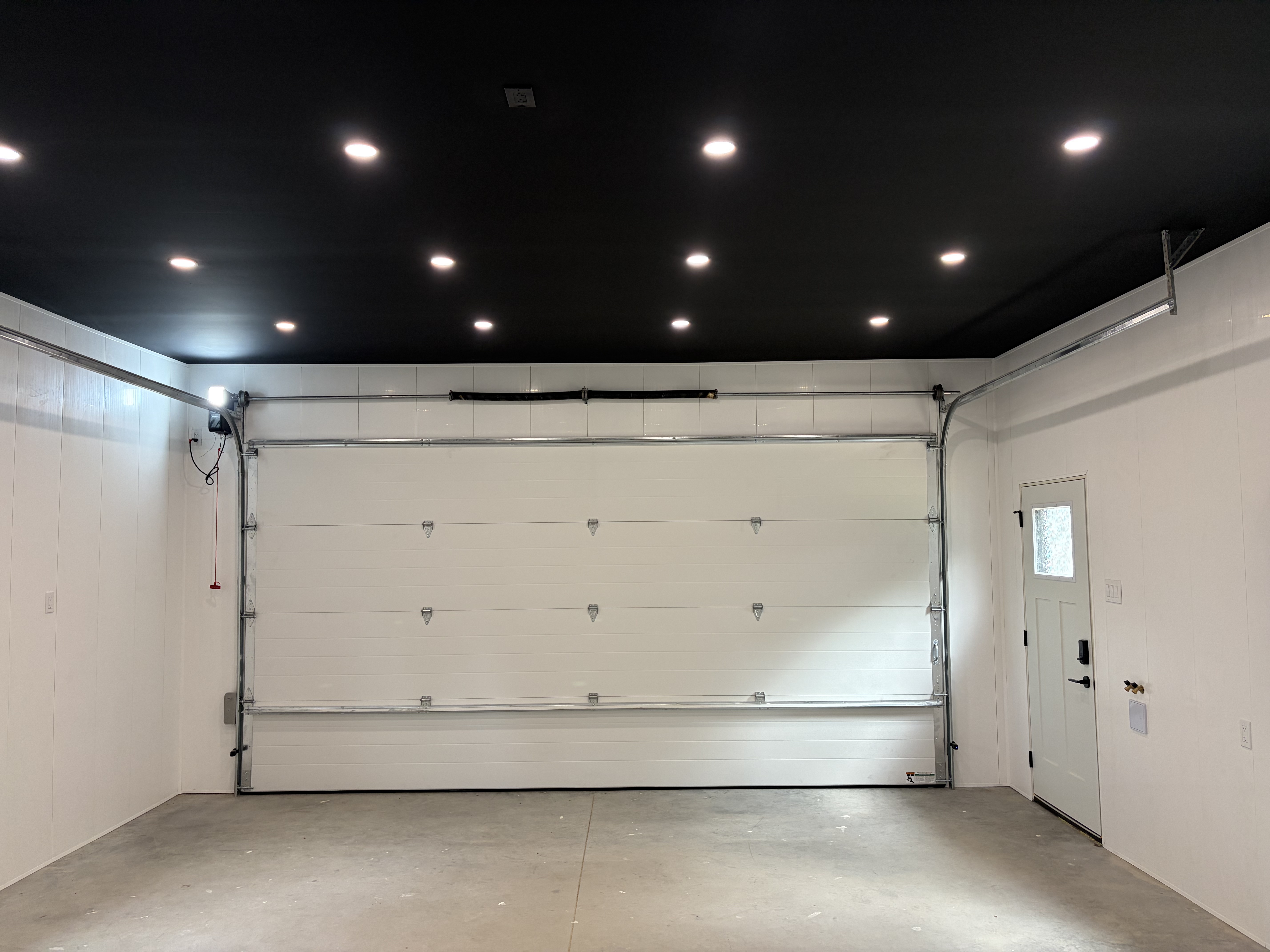Garage interior with black ceiling pot lights and slatwall storage