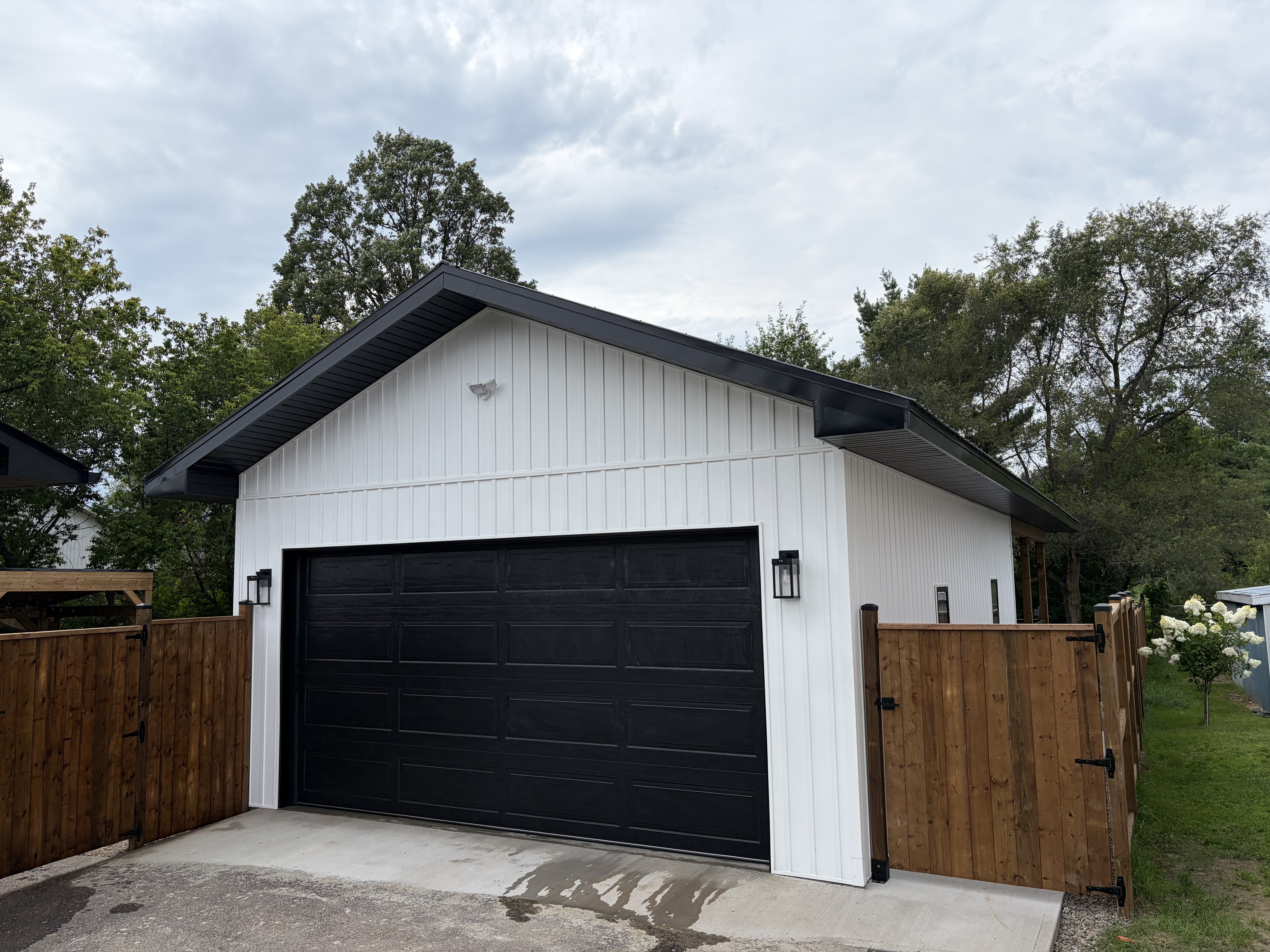 Custom garage front with black door and cedar fence gates