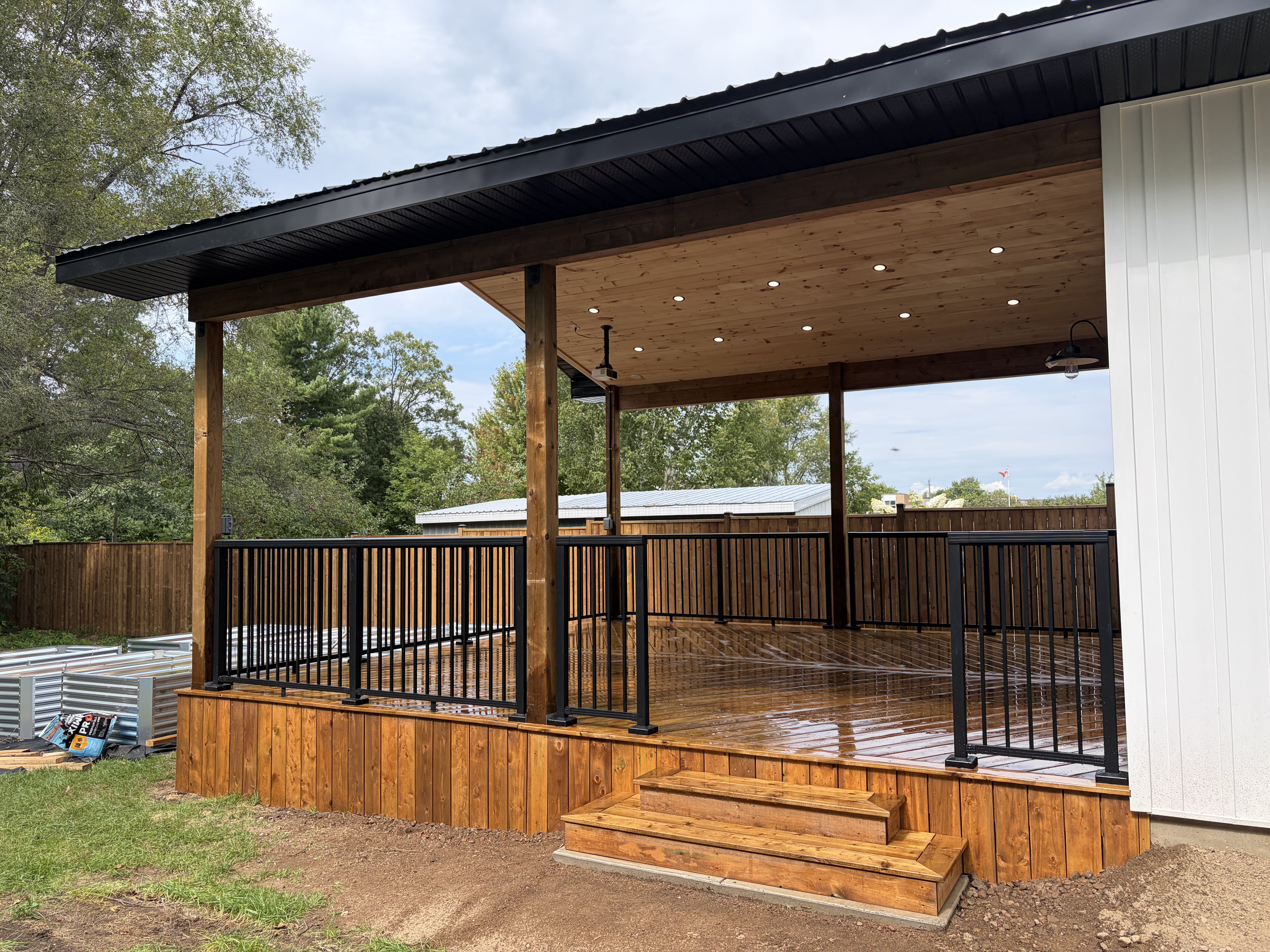 Covered deck with black aluminum railing and cedar steps