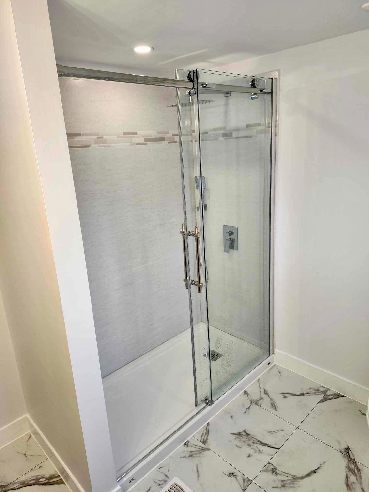 Glass shower with sliding door and marble floor