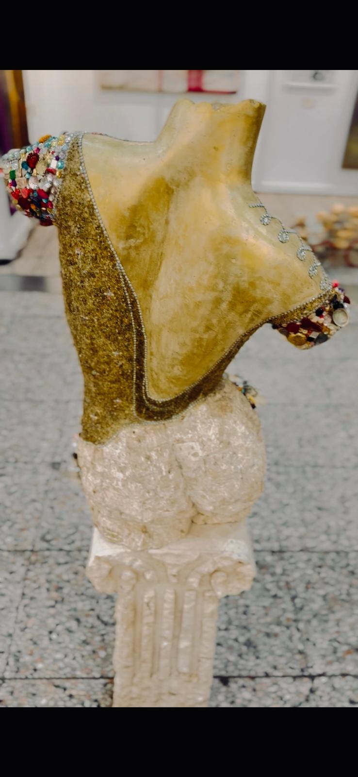 Side view of gold and gemstone bust on classical column in gallery