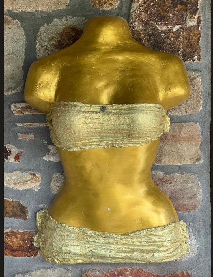 Golden bust with bandage-like wrapping on stone wall