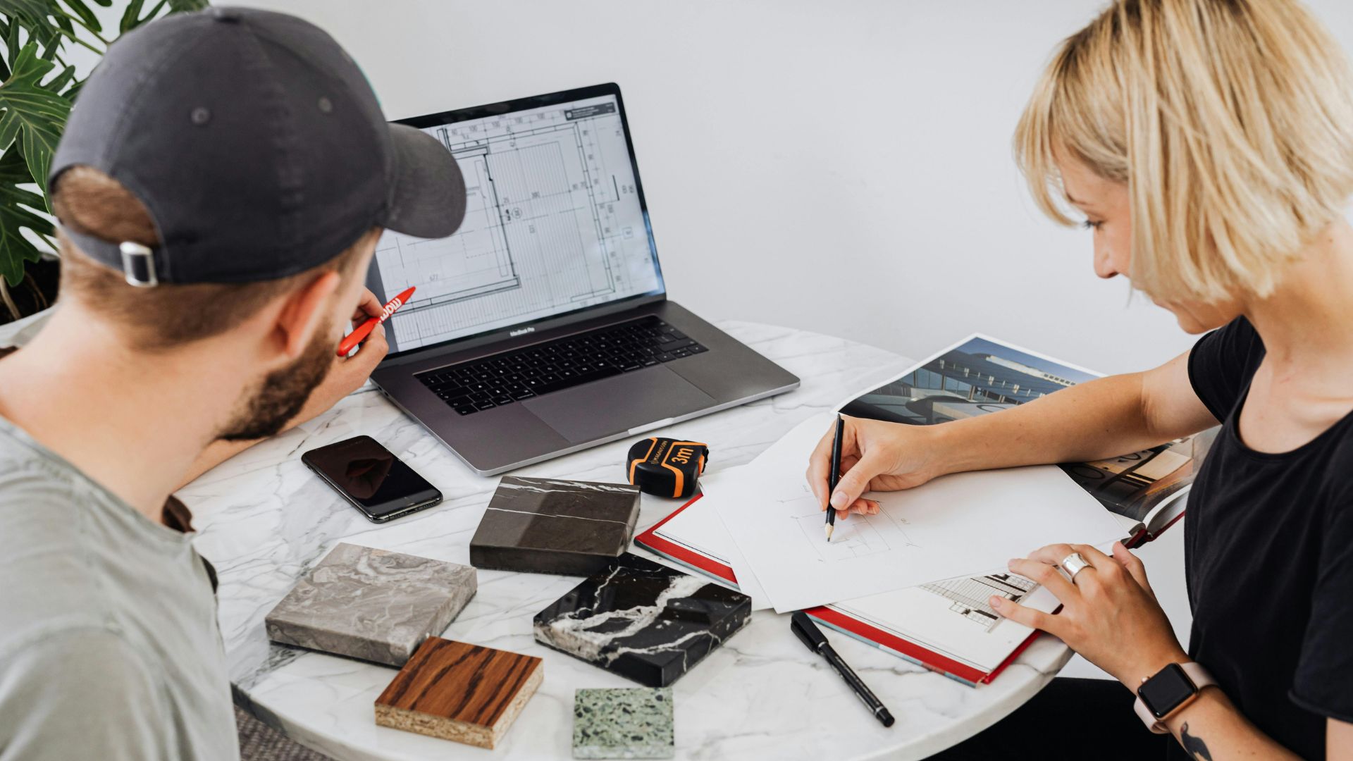 Två personer planerar vid bord med laptop – skillnaden mellan strategi och handlingsplan