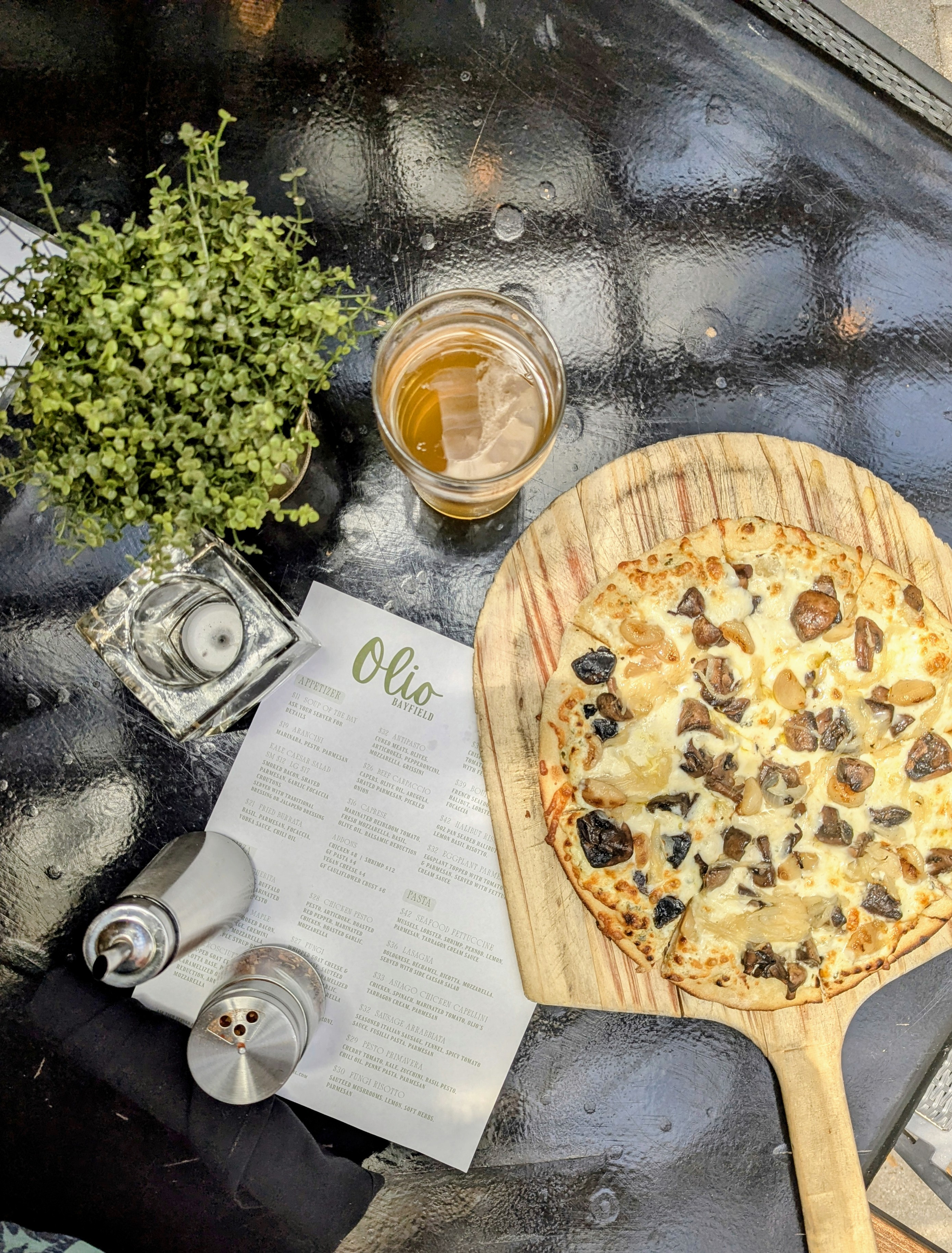 Olio pizza on a wooden board with the menu on the patio