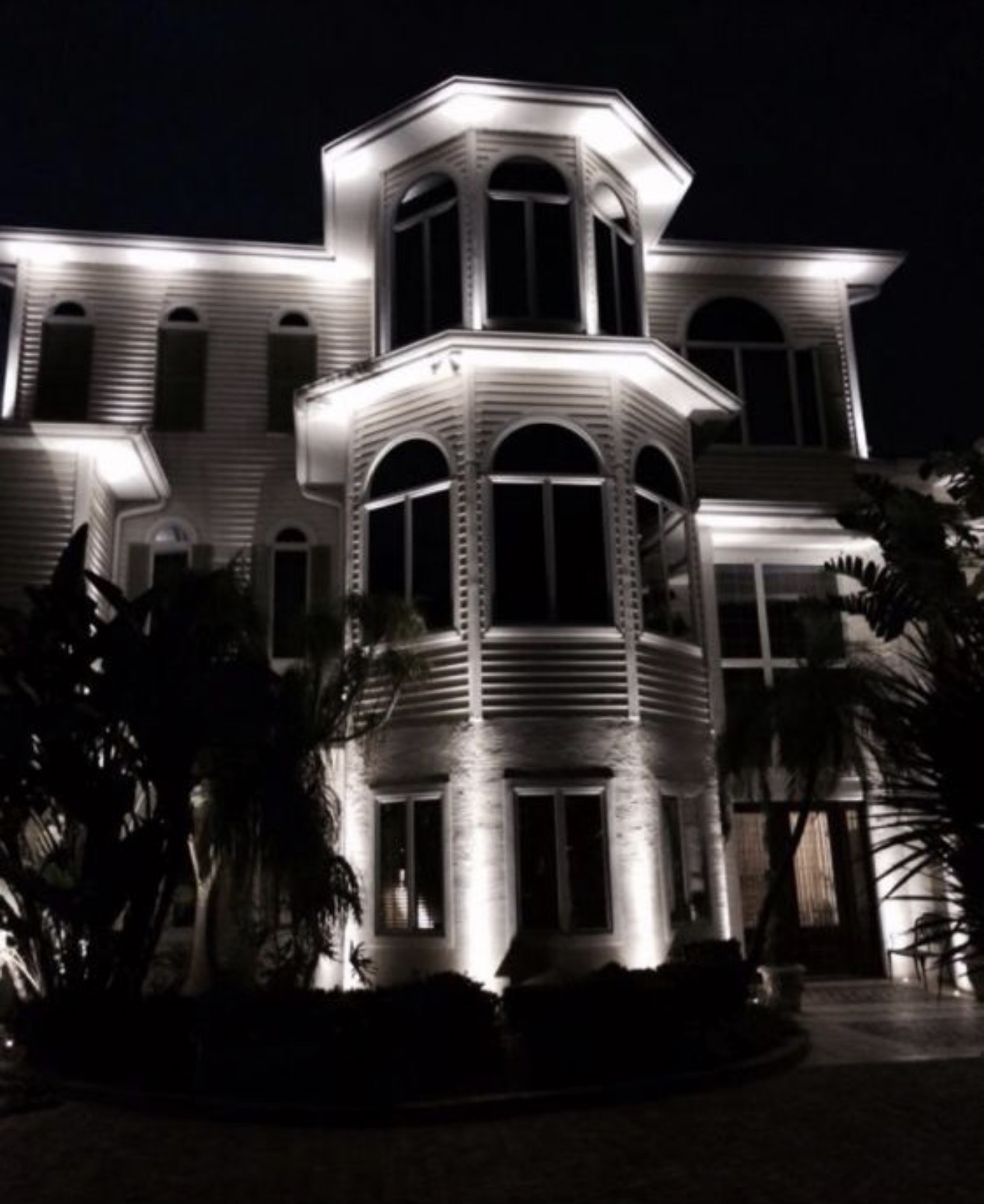 Dramatic 3-story waterfront home with full architectural LED uplighting at night