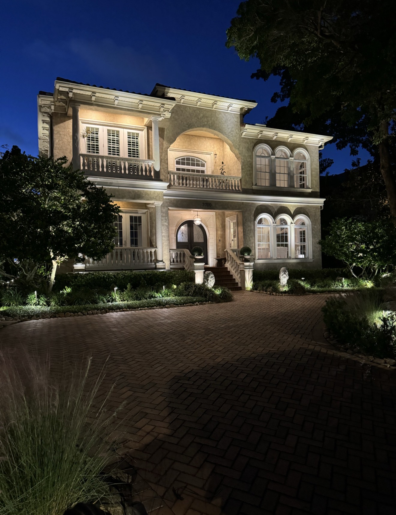 Kevin Harrington Shark Tank luxury estate Tampa Bay full architectural outdoor lighting by LED Artistry — two-story Mediterranean home with brick driveway, landscape uplighting, and facade wash at night
