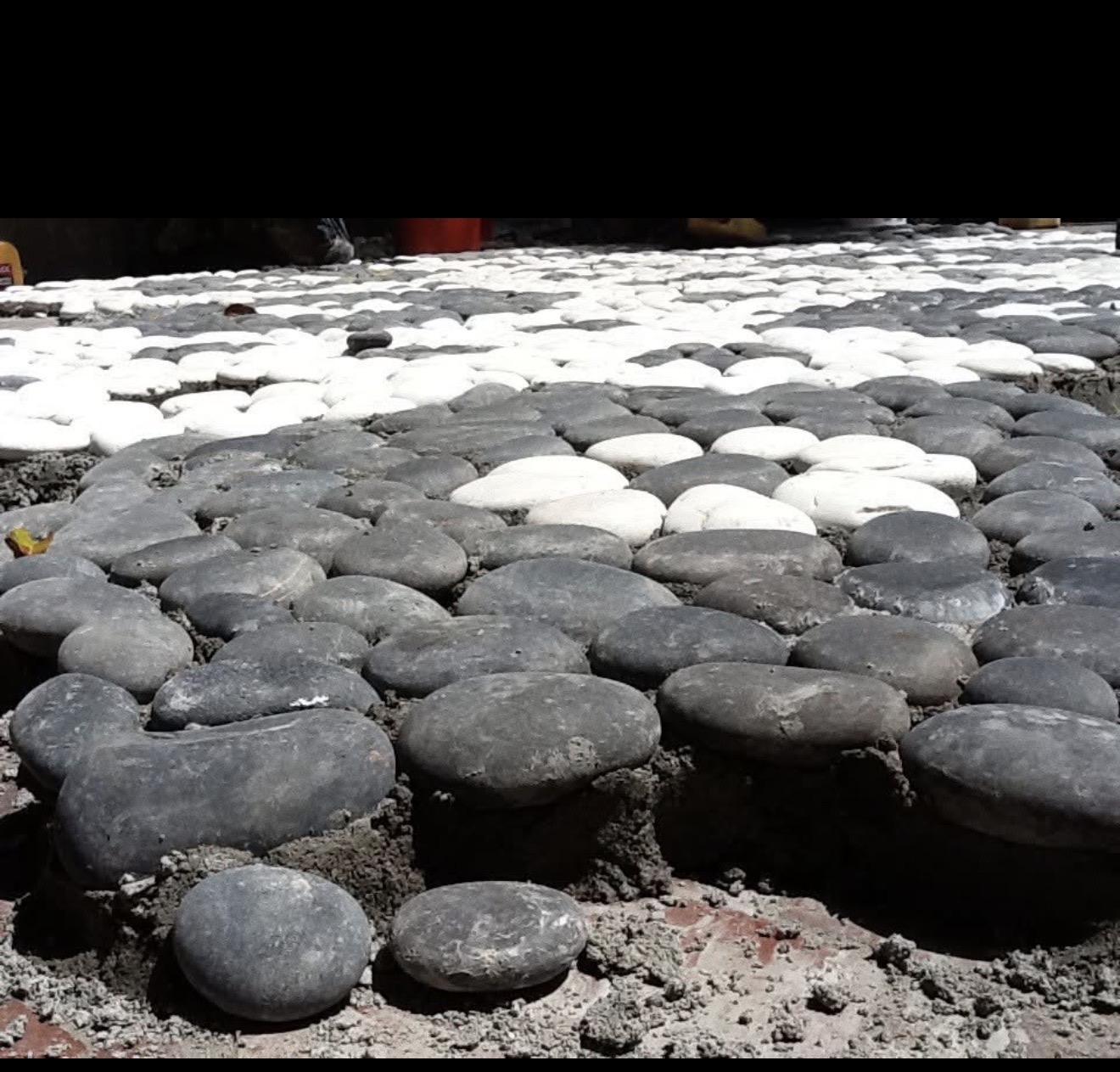 Hand-set black and white river stone pebble mosaic being installed at Steinbrenner estate Davis Islands Tampa Bay — Moroccan pattern replication in progress by LED Artistry