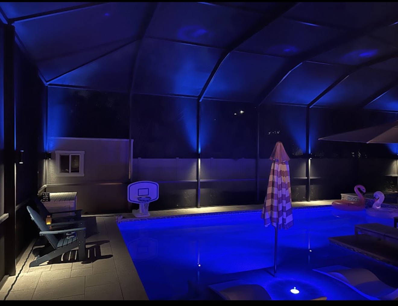 Pool cage with deep purple RGBW LED uplighting and pool reflection at night Tampa Bay