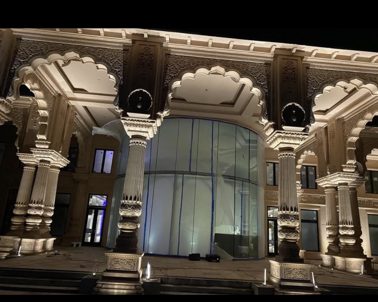 Surya Estates Dr. Kiran Patel Carrollwood Tampa exterior palace facade at night — ornate Rajasthani carved columns and Mughal arched portico lit by LED Artistry uplights