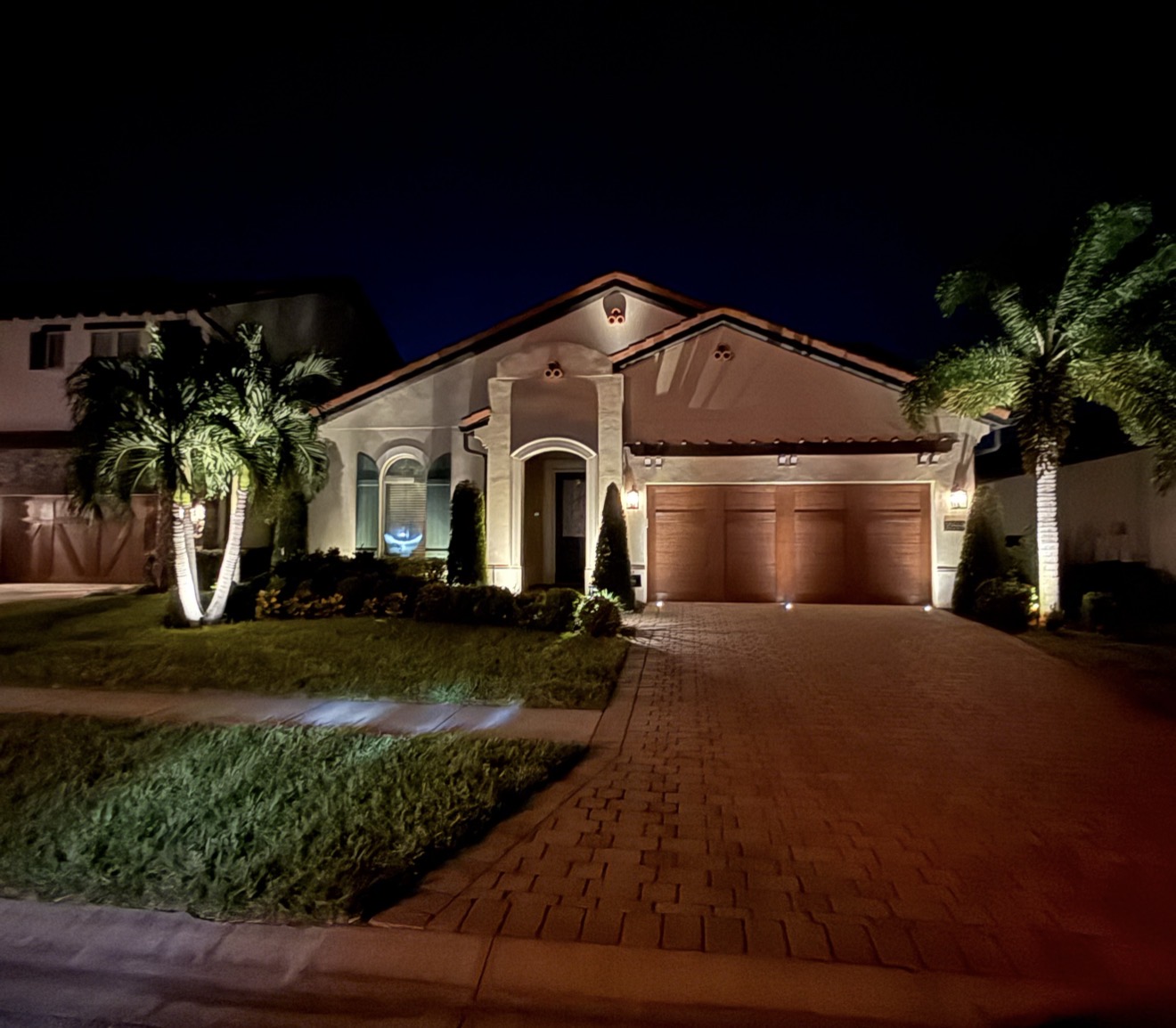 Royal Cypress Preserve Orlando single-story Mediterranean luxury home with warm white LED uplighting and palm trees by LED Artistry near Disney World