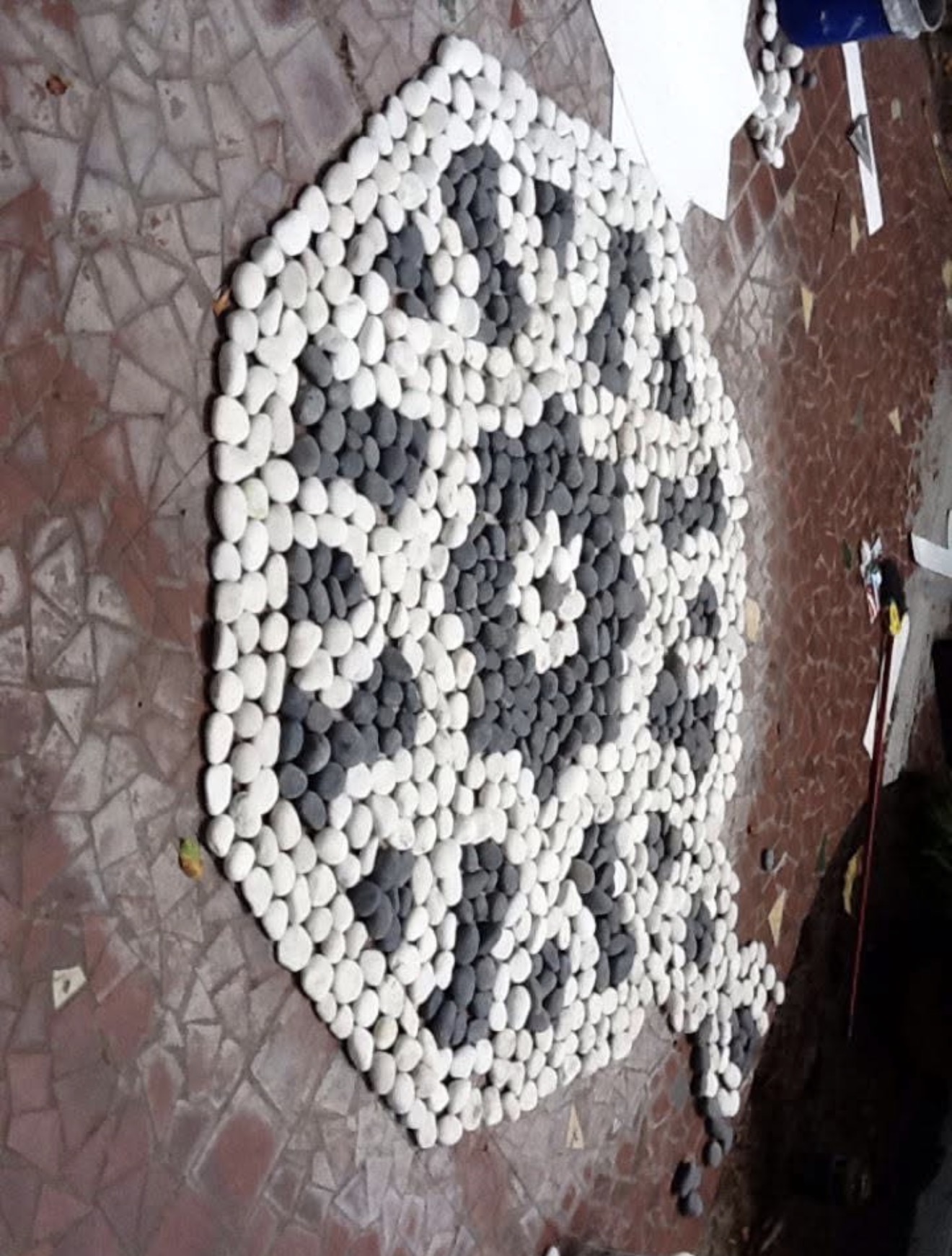 Moroccan pebble medallion being hand-set at Steinbrenner estate Tampa — single star medallion in black and white river stone on terracotta tile base