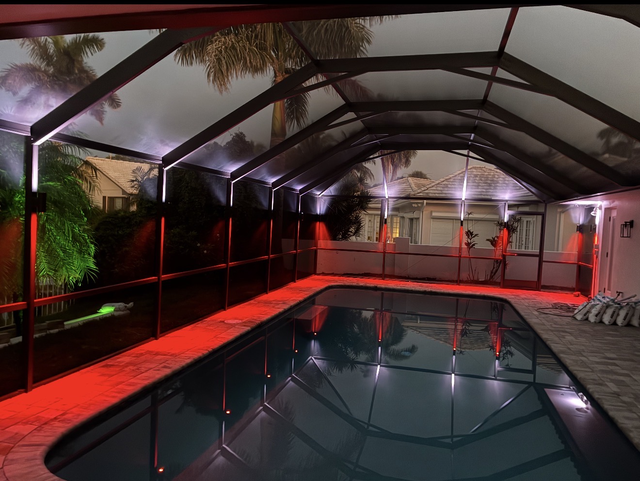 Pool cage with dramatic red RGBW LED color lighting at night, pool reflection Tampa Bay