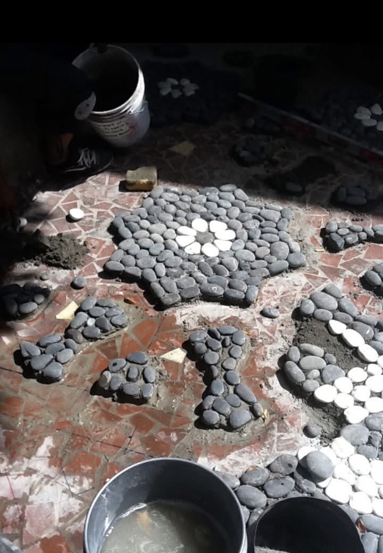Multiple Moroccan star patterns being installed simultaneously at Steinbrenner estate courtyard Davis Islands Tampa — pebble mosaic work in progress LED Artistry