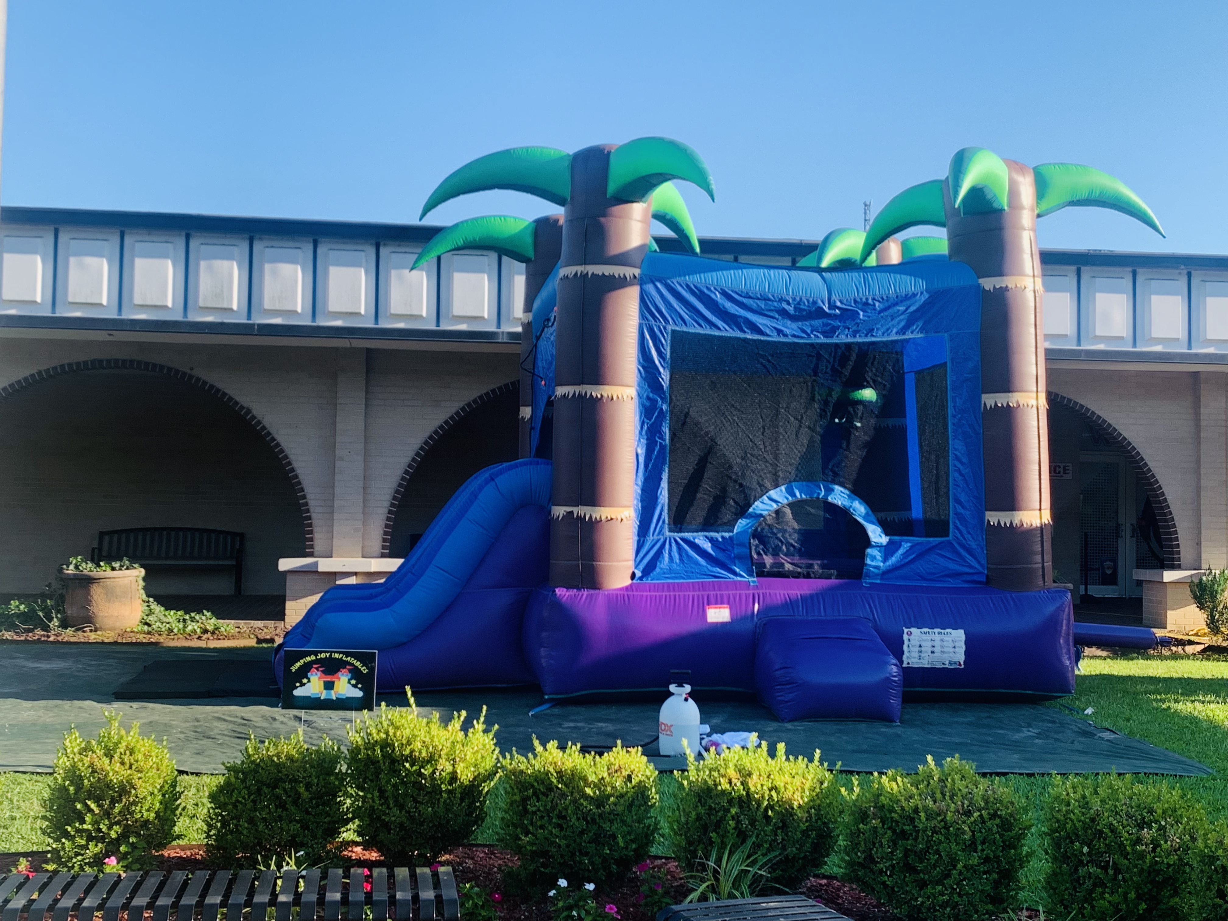 Tropical Storm combo unit set up outside a venue with the Jumping Joy Inflatables yard sign