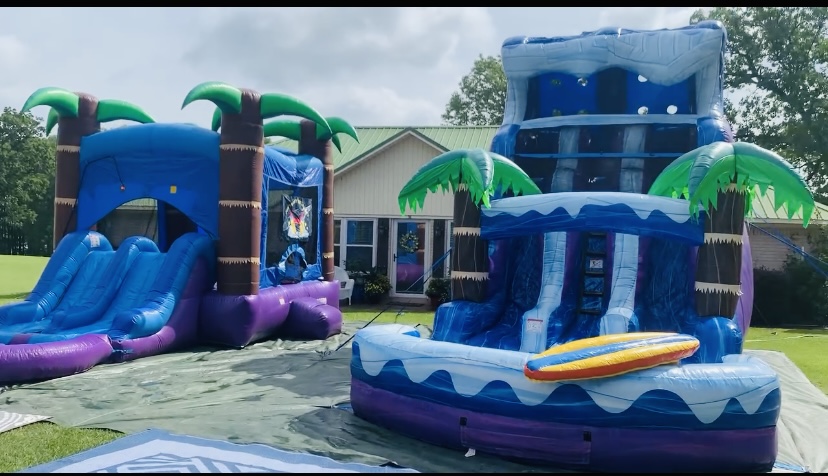 Tropical Storm combo unit and Palm Tree Plunge water slide set up side by side at a backyard party