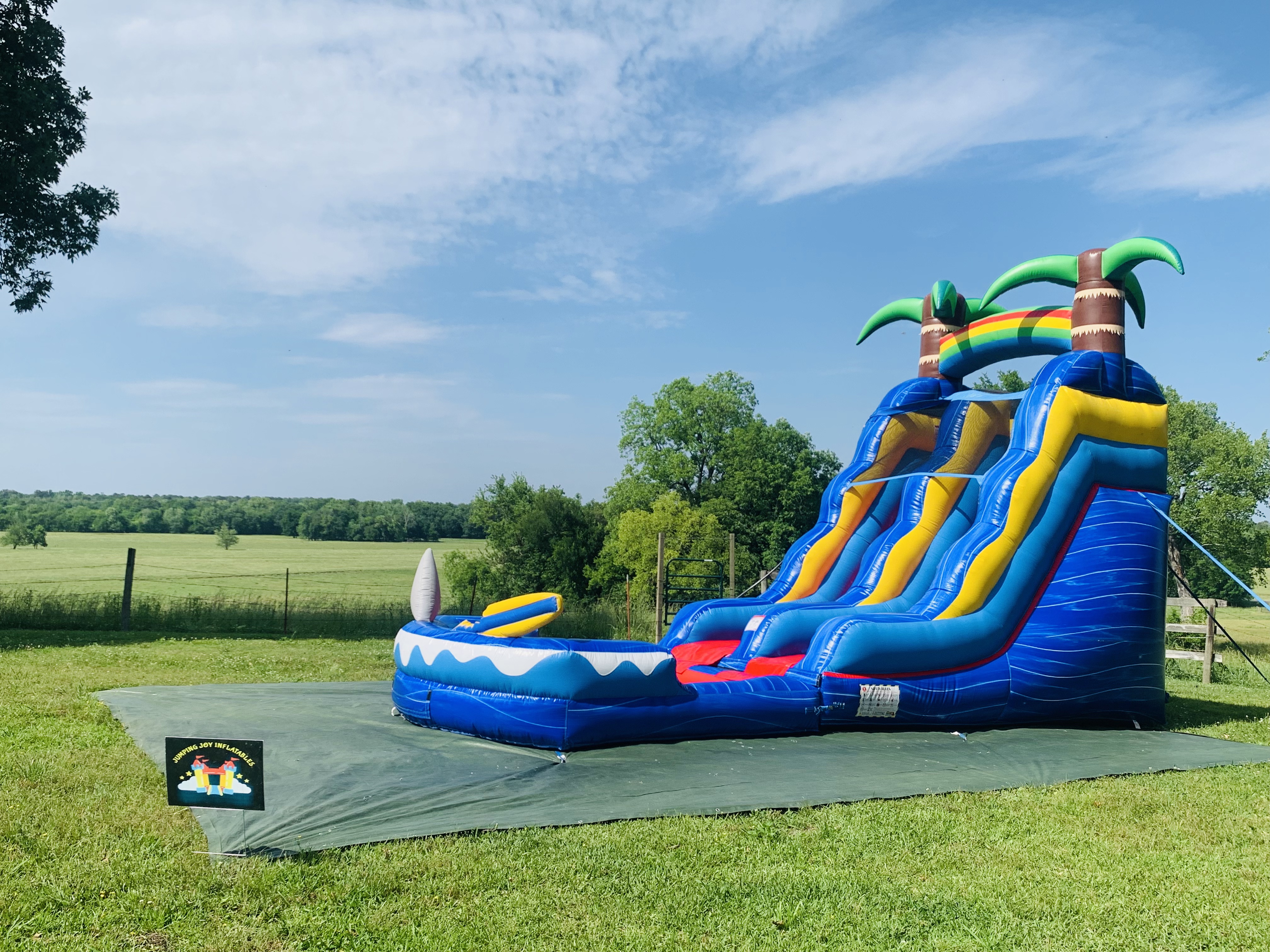 Shark Attack single lane water slide with palm trees and splash pool set up in open field