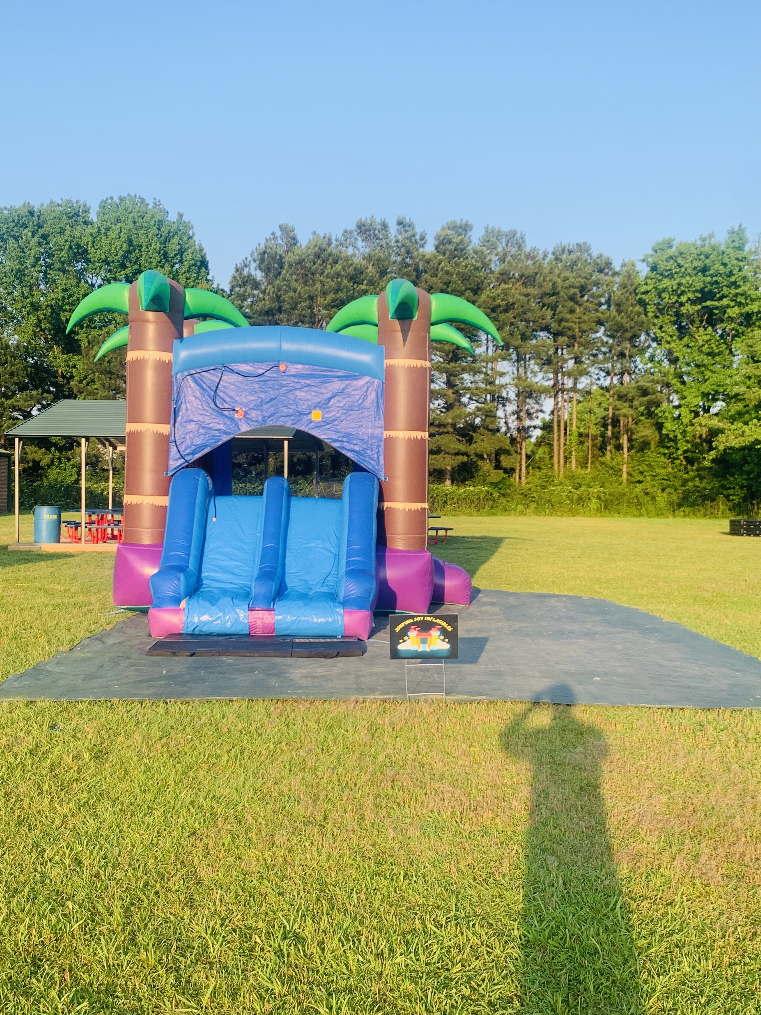 Tropical Storm combo unit set up on green grass at a park with Jumping Joy Inflatables yard sign