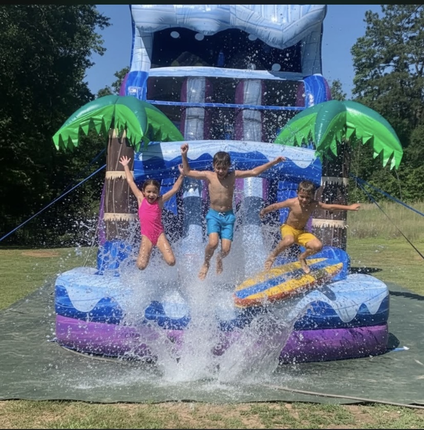 Kids jumping and splashing in the Palm Tree Plunge water slide splash pool on a sunny day