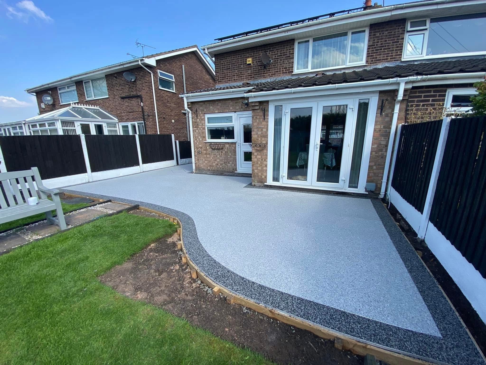Large resin bound patio with curved edge and dark border — back garden residential