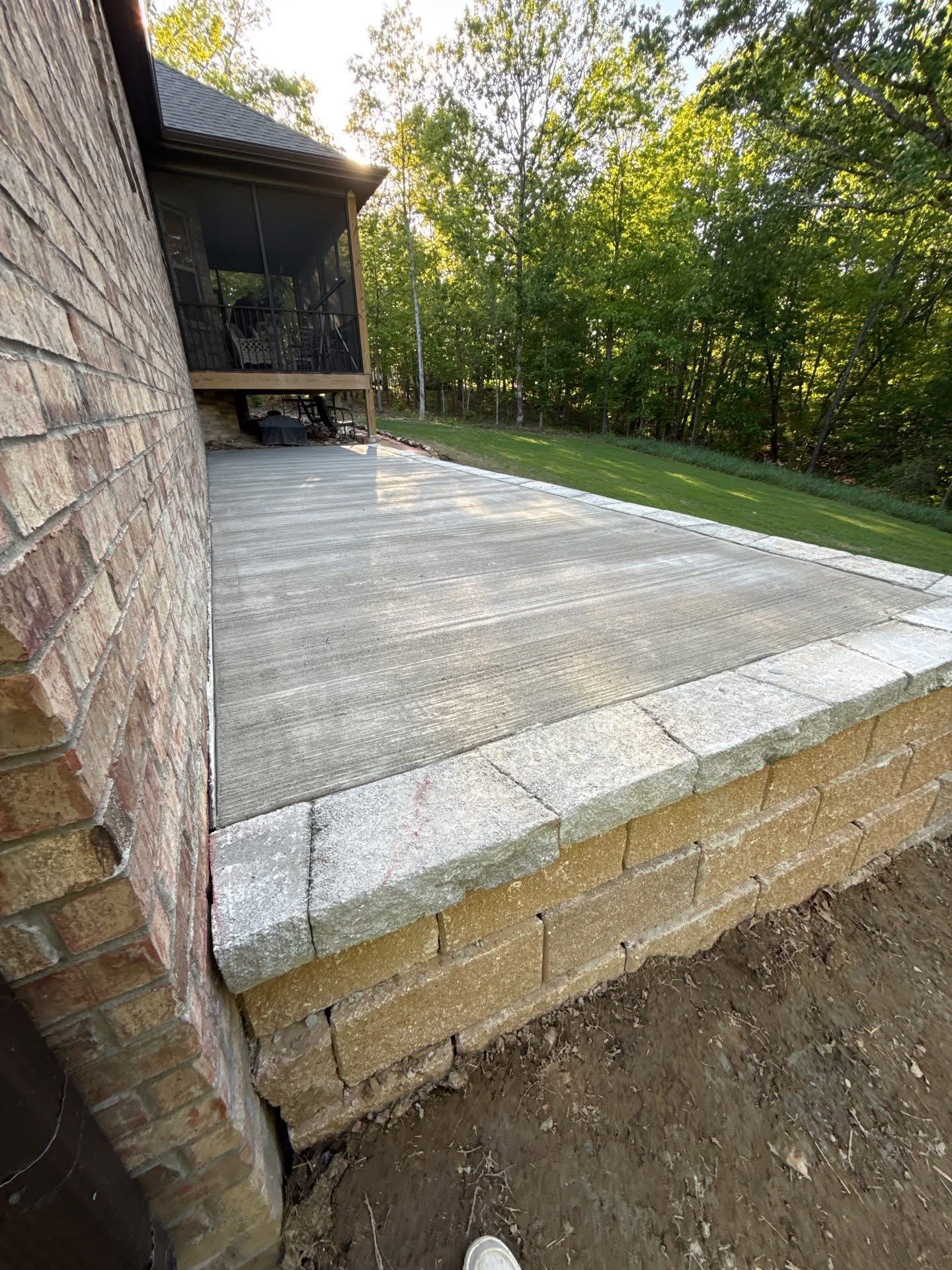 Retaining wall with concrete pad and block construction alongside a brick home, built by Stukes Construction